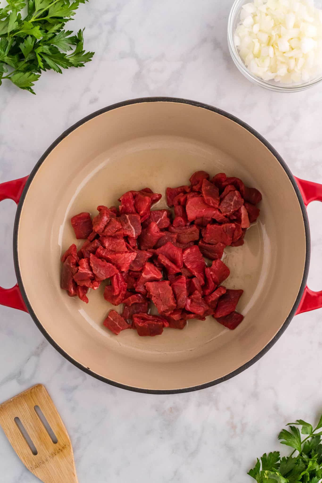 raw steak pieces added to a dutch oven