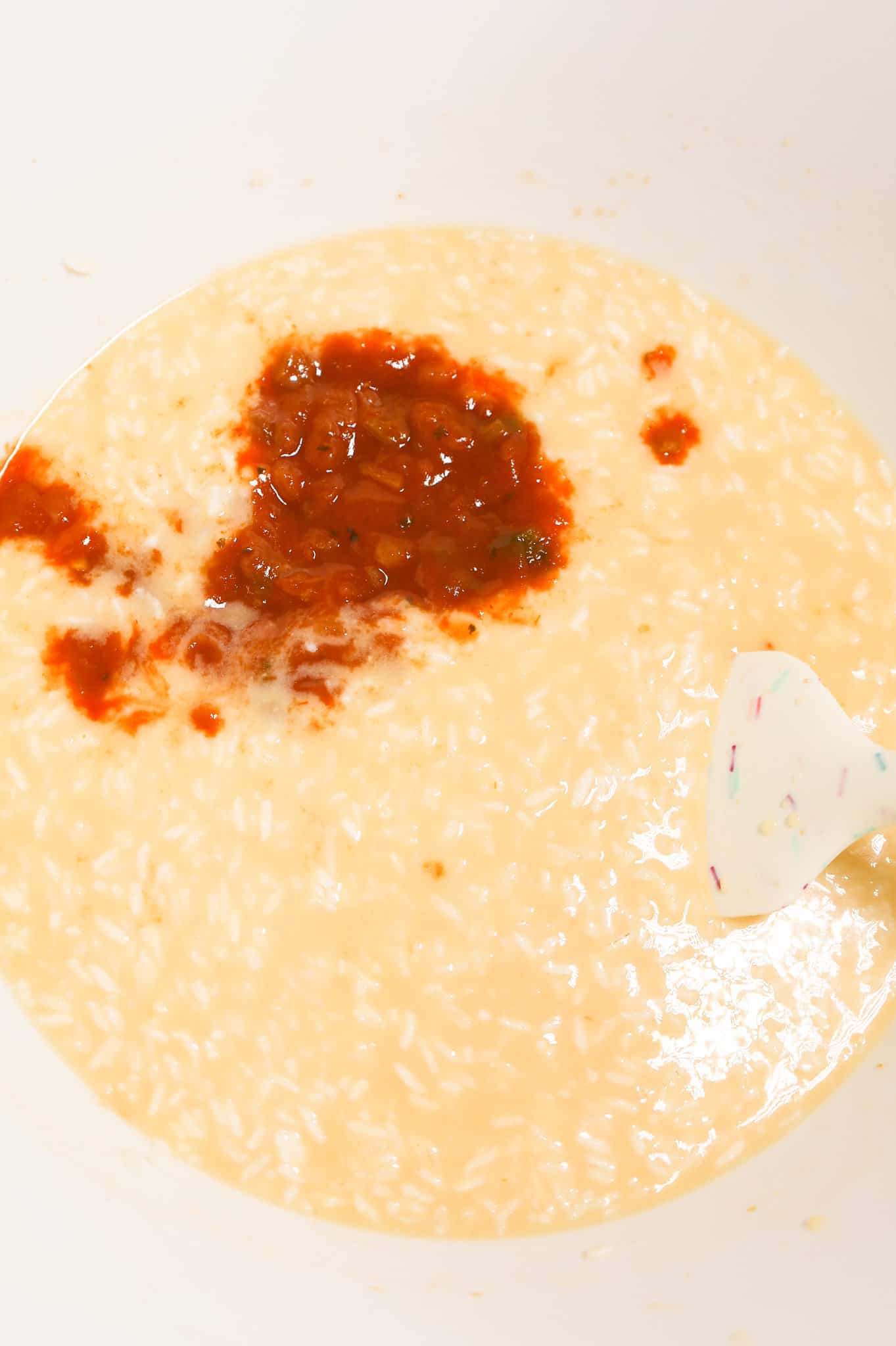 salsa on top of rice and soup mixture in a mixing bowl