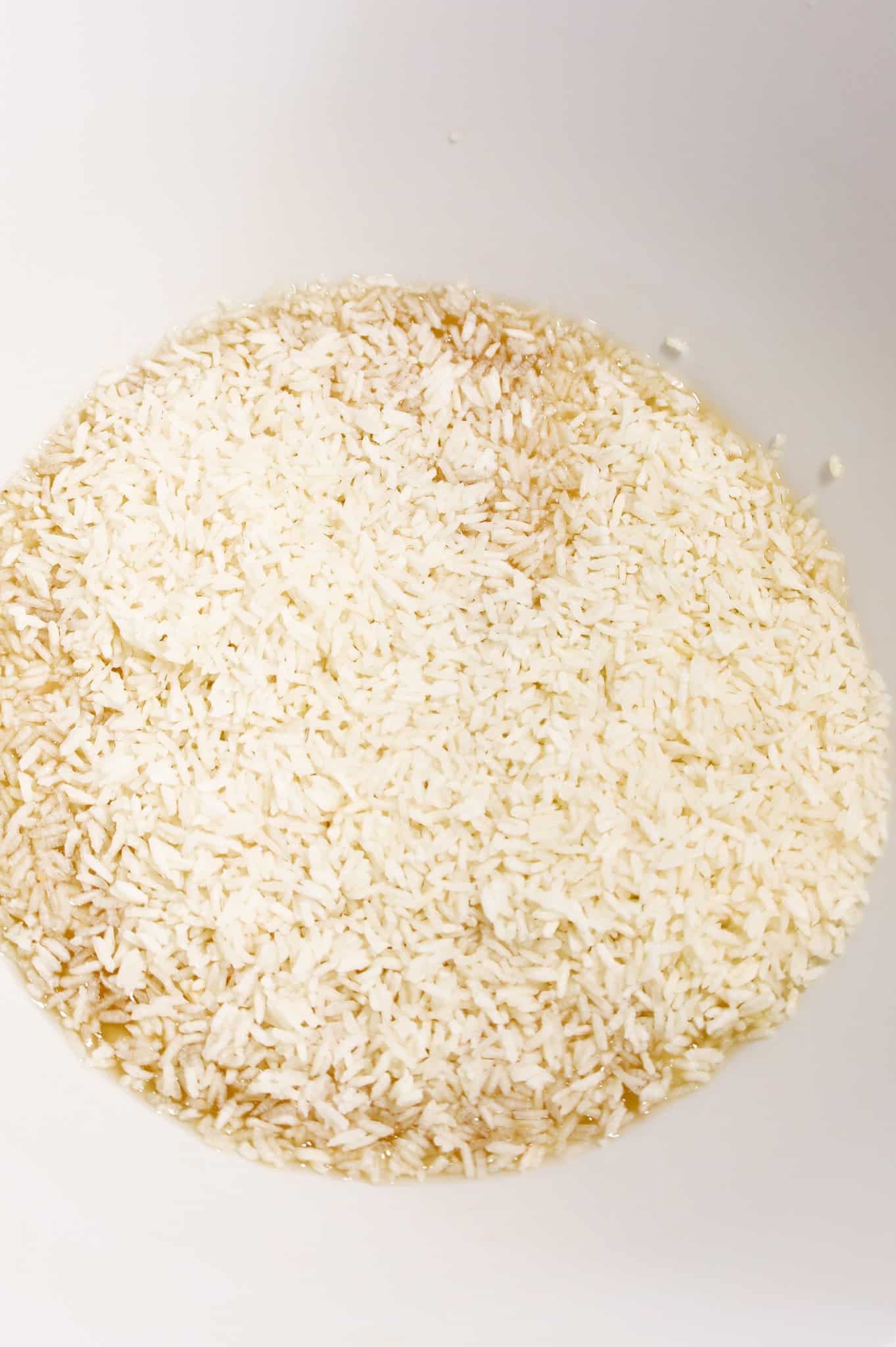 instant rice on top of soup mixture in a mixing bowl