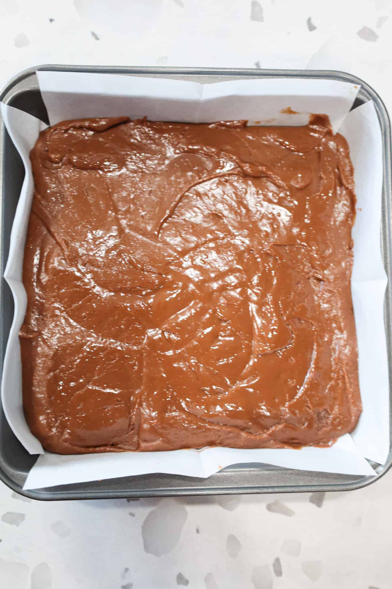milk chocolate mixture spread in a parchment lined baking pan