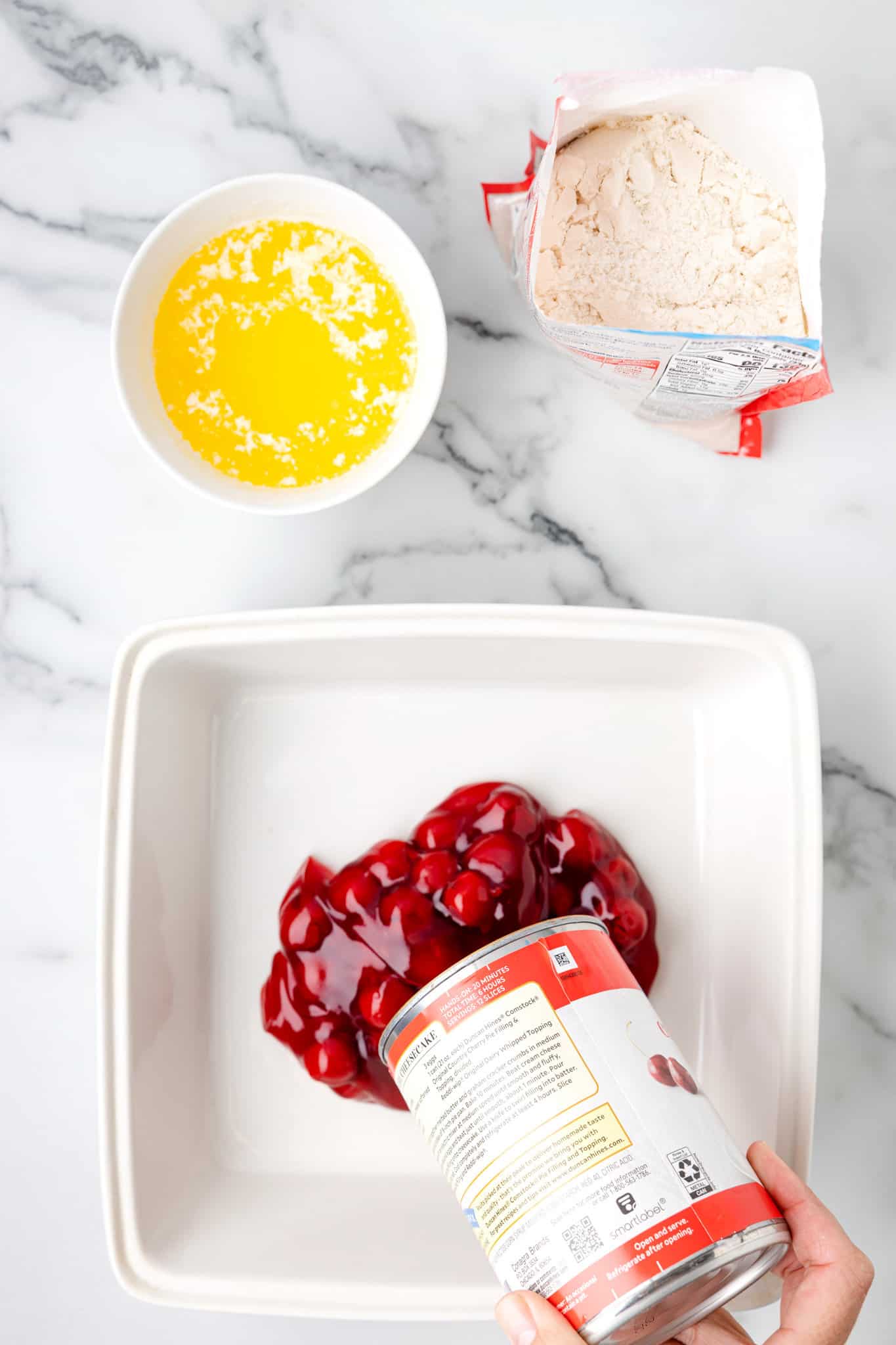 pouring can of cherry pie filling into baking dish