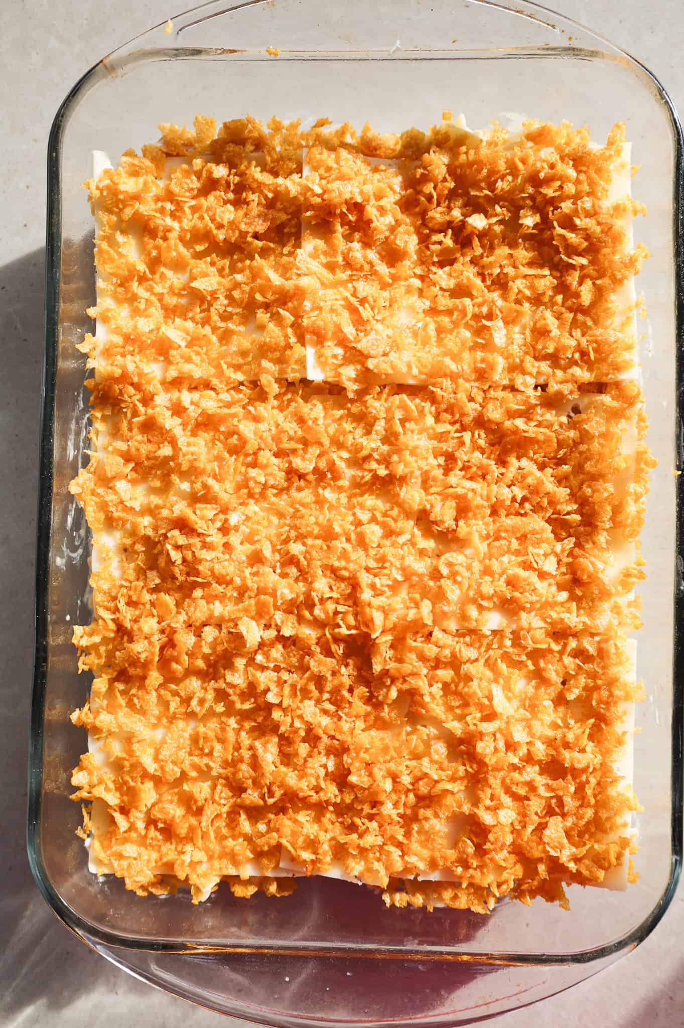 crumbled corn flakes on top of ham noodle casserole in a baking dish