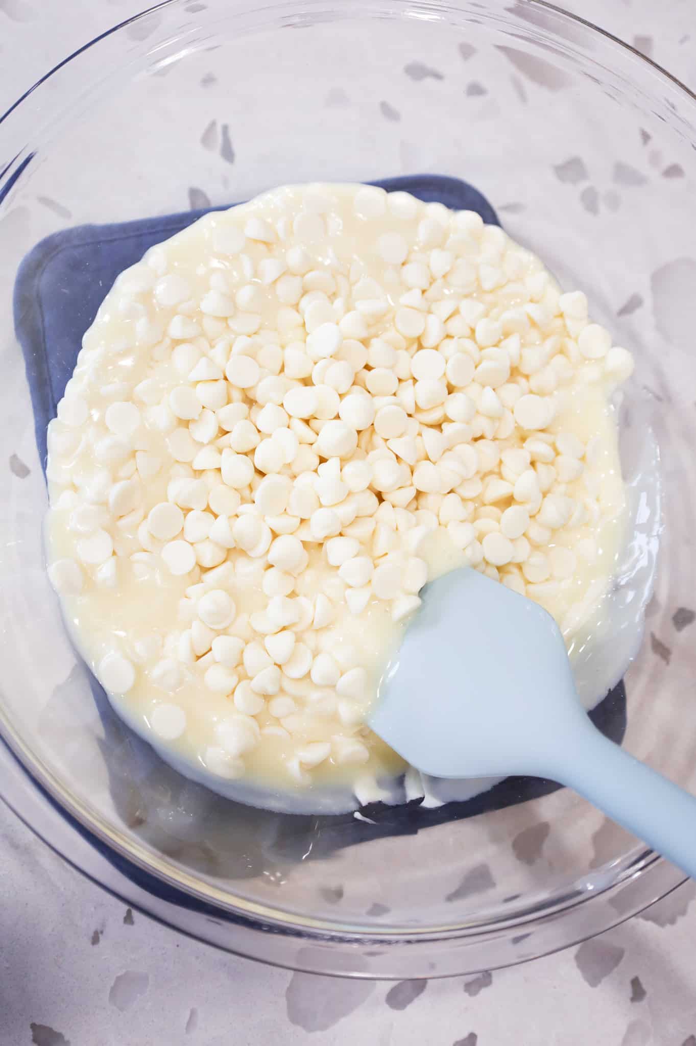 stirring sweetened condensed milk and white chocolate chips in a mixing bowl