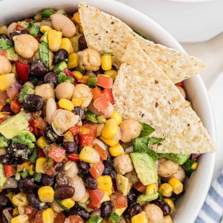 Cowboy Caviar is a delicious cold dip recipe loaded with a variety of beans, avocado, tomatoes, corn, peppers, onions and fresh cilantro.