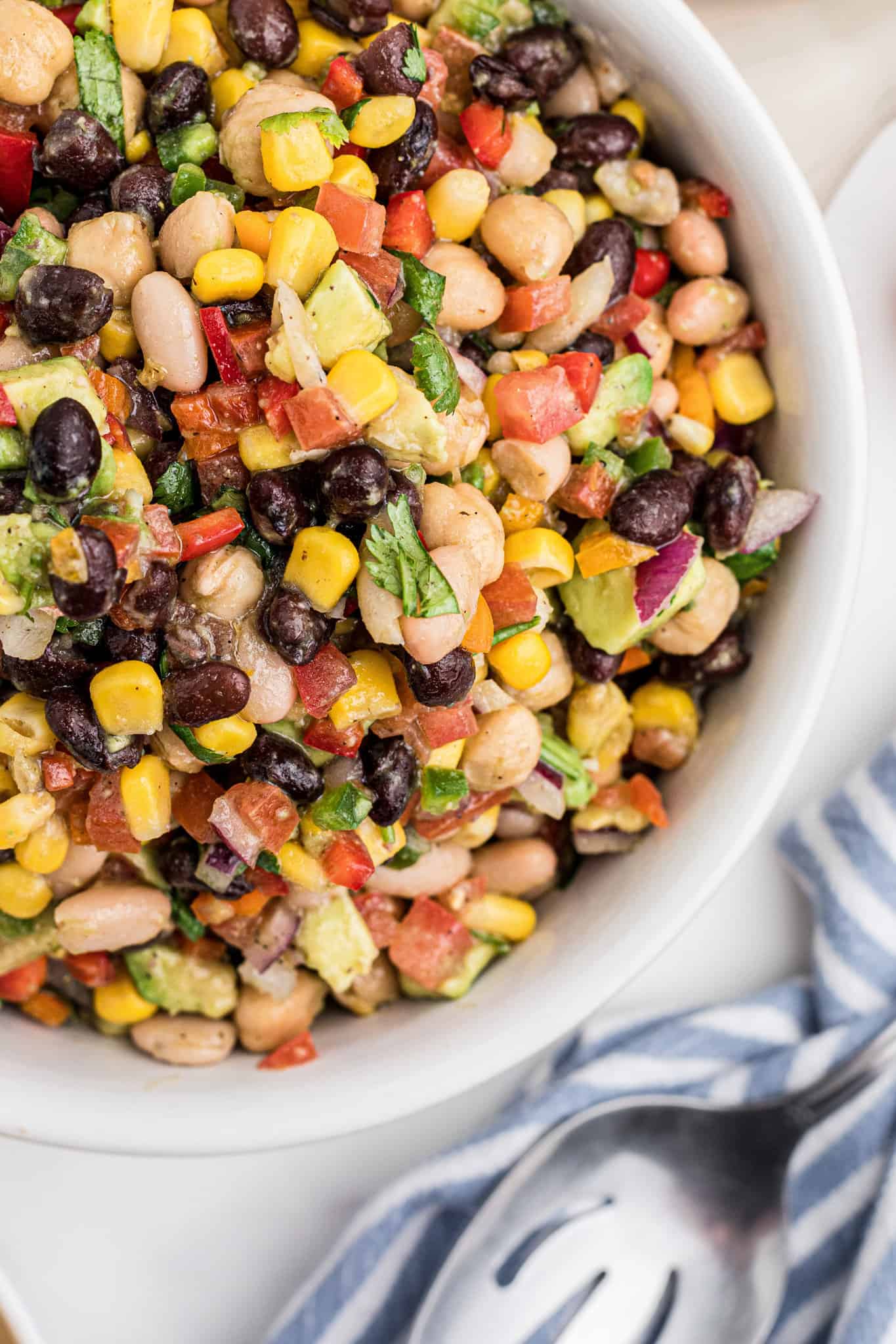 Cowboy Caviar is a delicious cold dip recipe loaded with a variety of beans, avocado, tomatoes, corn, peppers, onions and fresh cilantro.