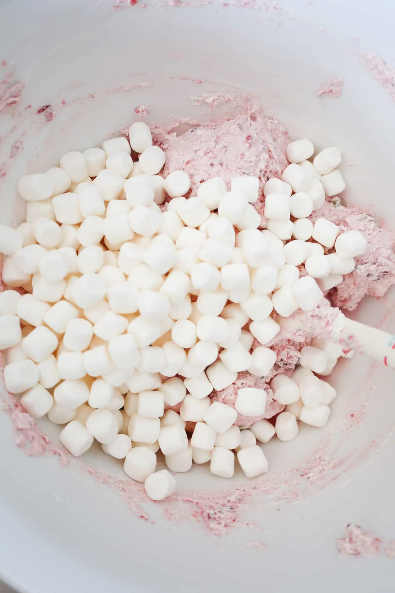 mini marshmallows on top of Cool whip and cranberry sauce mixture in a mixing bowl
