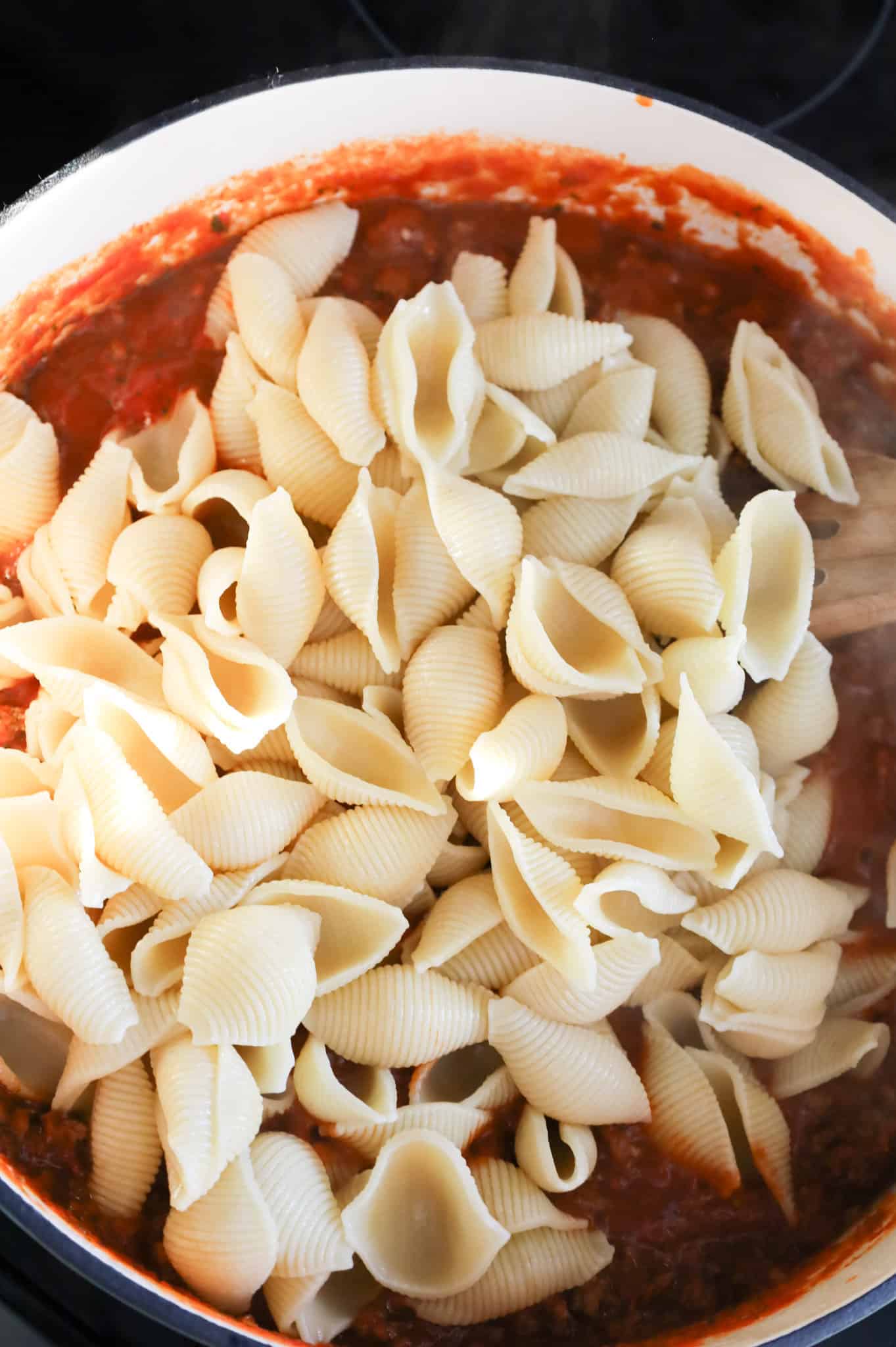 cooked pasta shells in a skillet with marinara and ground beef mixture