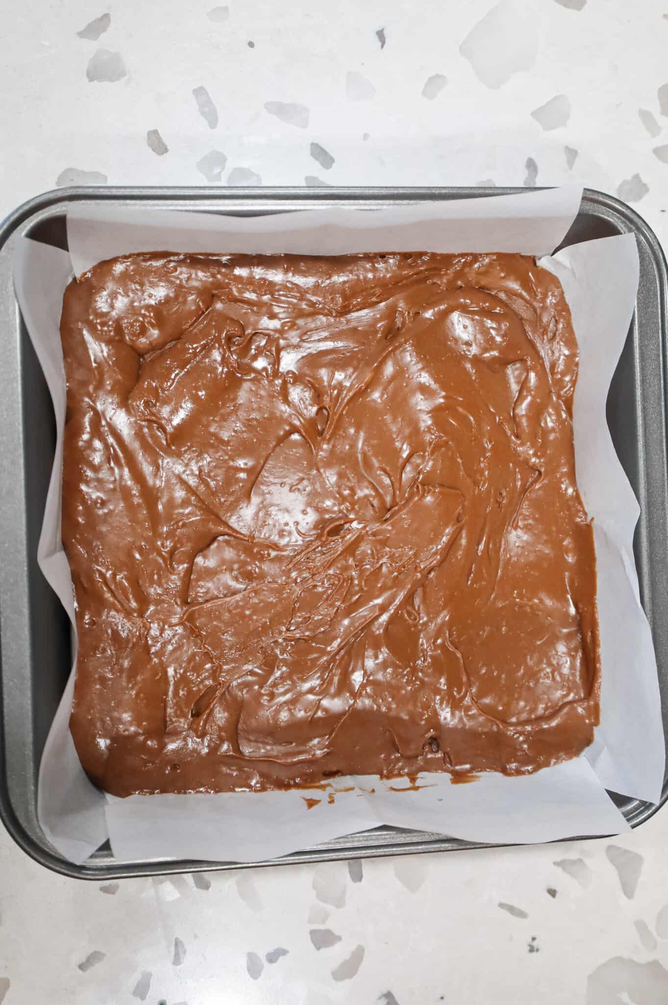 milk chocolate fudge mixture in a parchment lined baking pan