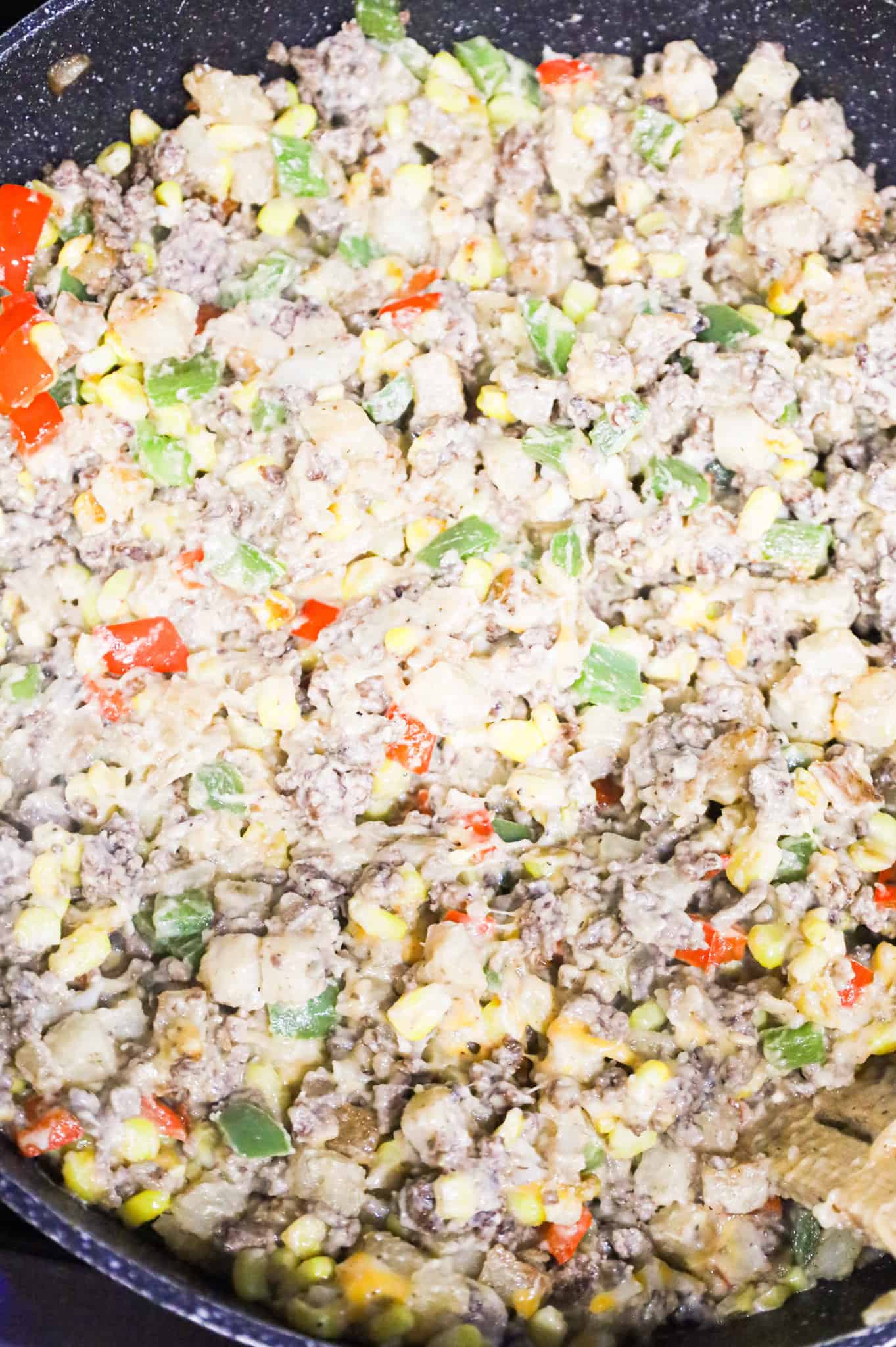 stirring cheese into ground beef and potato mixture in a skillet