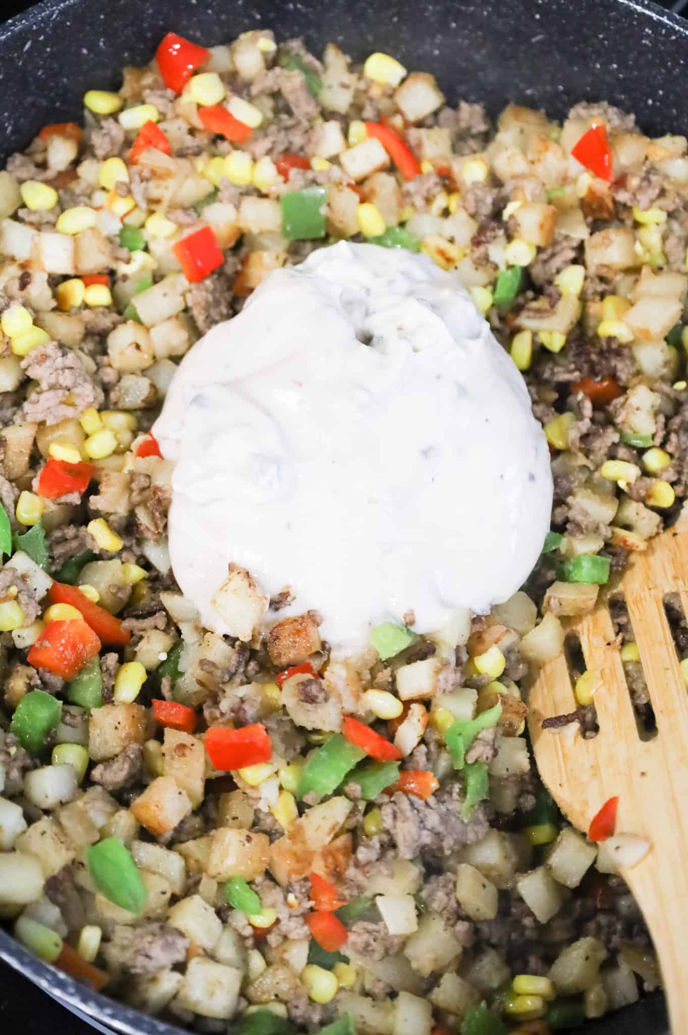 cream of mushroom soup on top of ground beef and potato mixture in a skillet