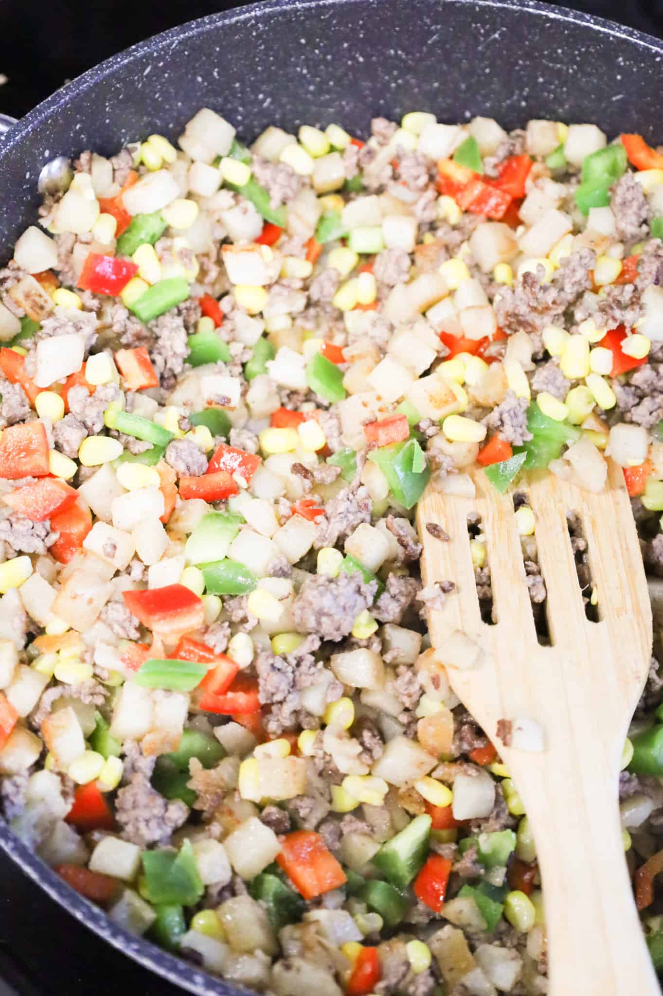 diced bell pepper, corn ground beef and potato mixture in a skillet