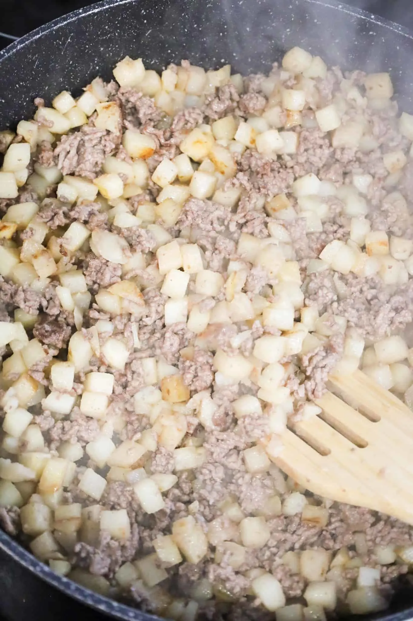 ground beef and diced potatoes cooking in a skillet