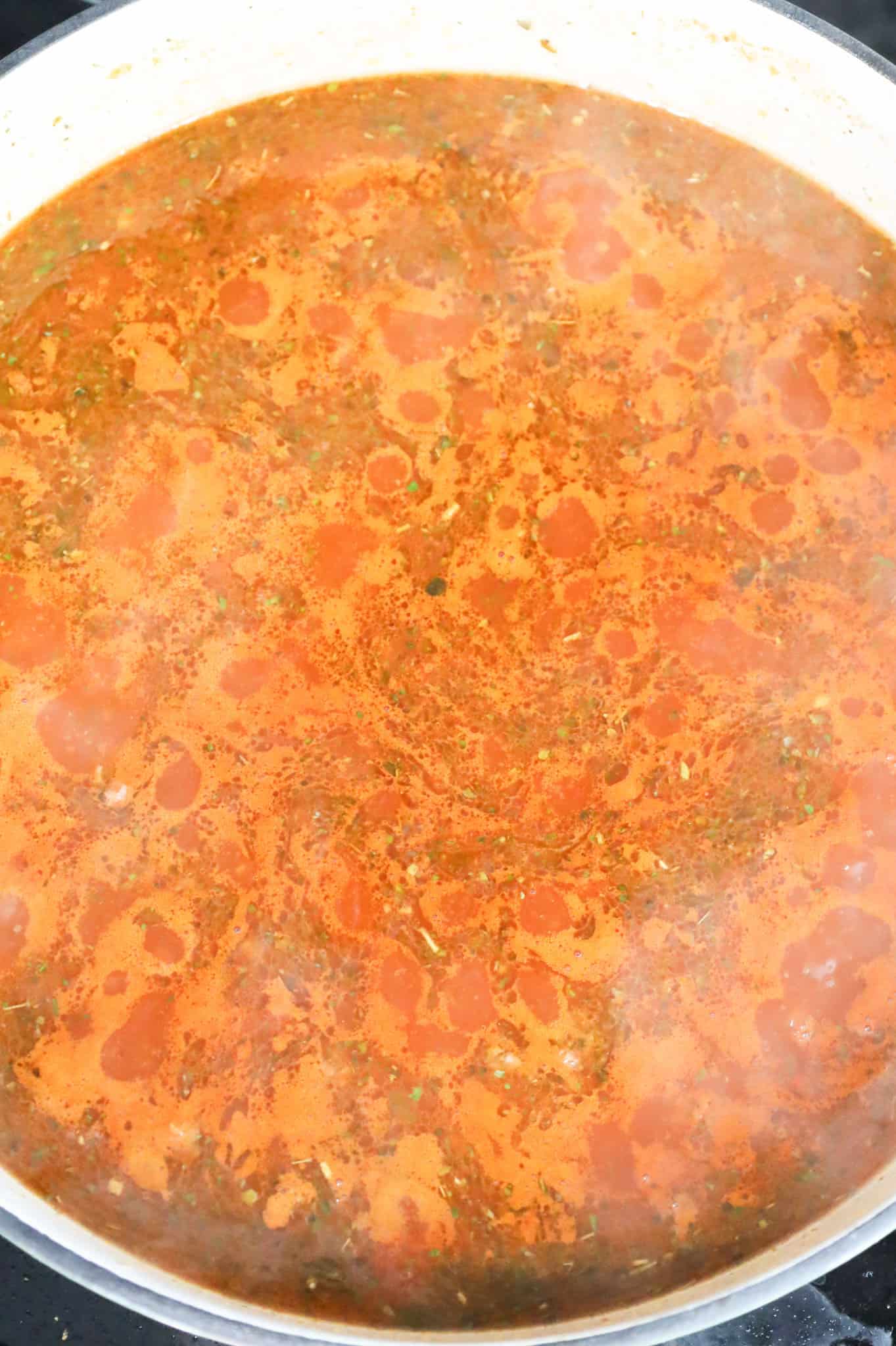 marinara and beef broth mixture bubbling in a skillet