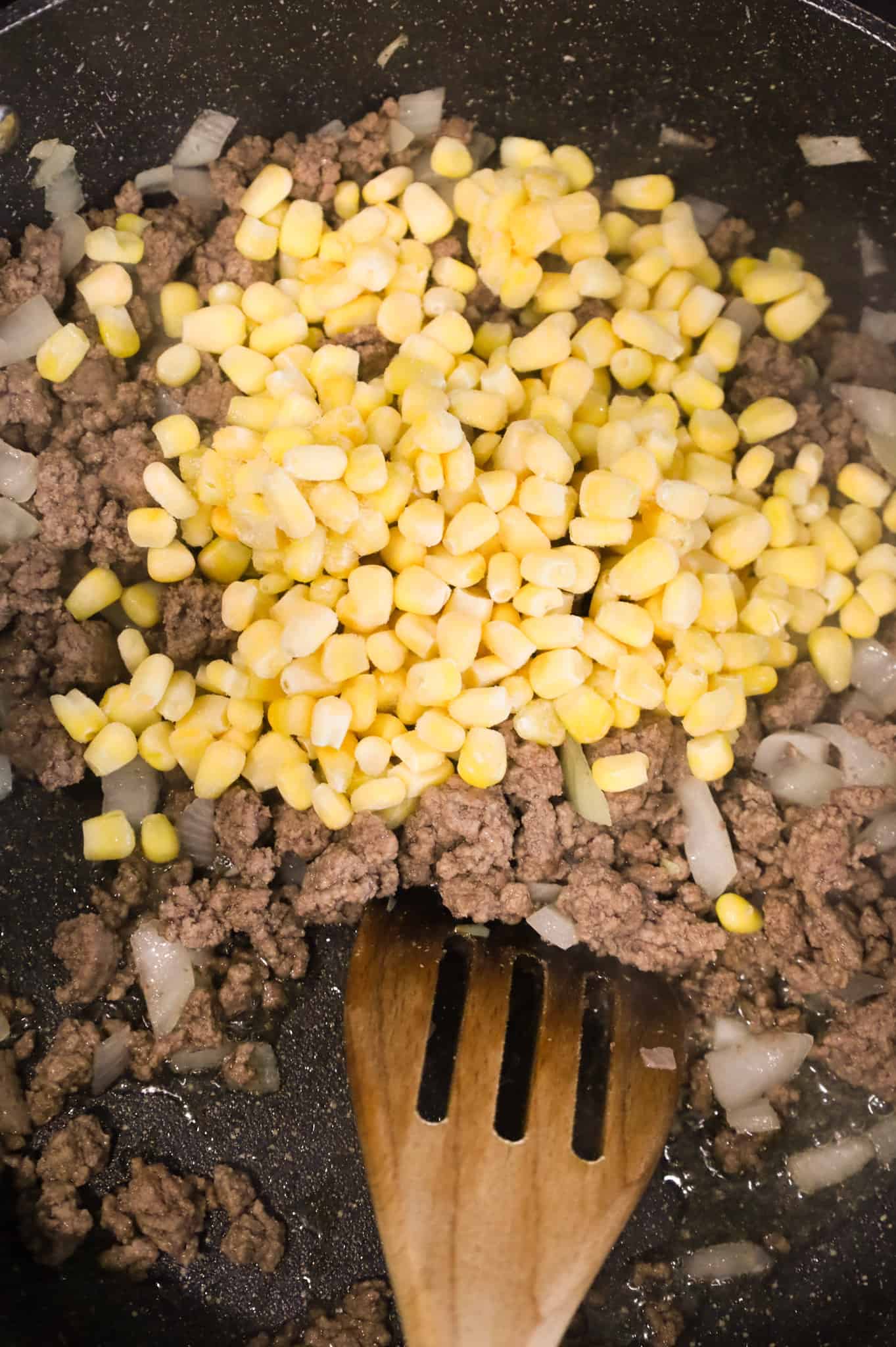 frozen corn kernels added to skillet with cooked ground beef and onions