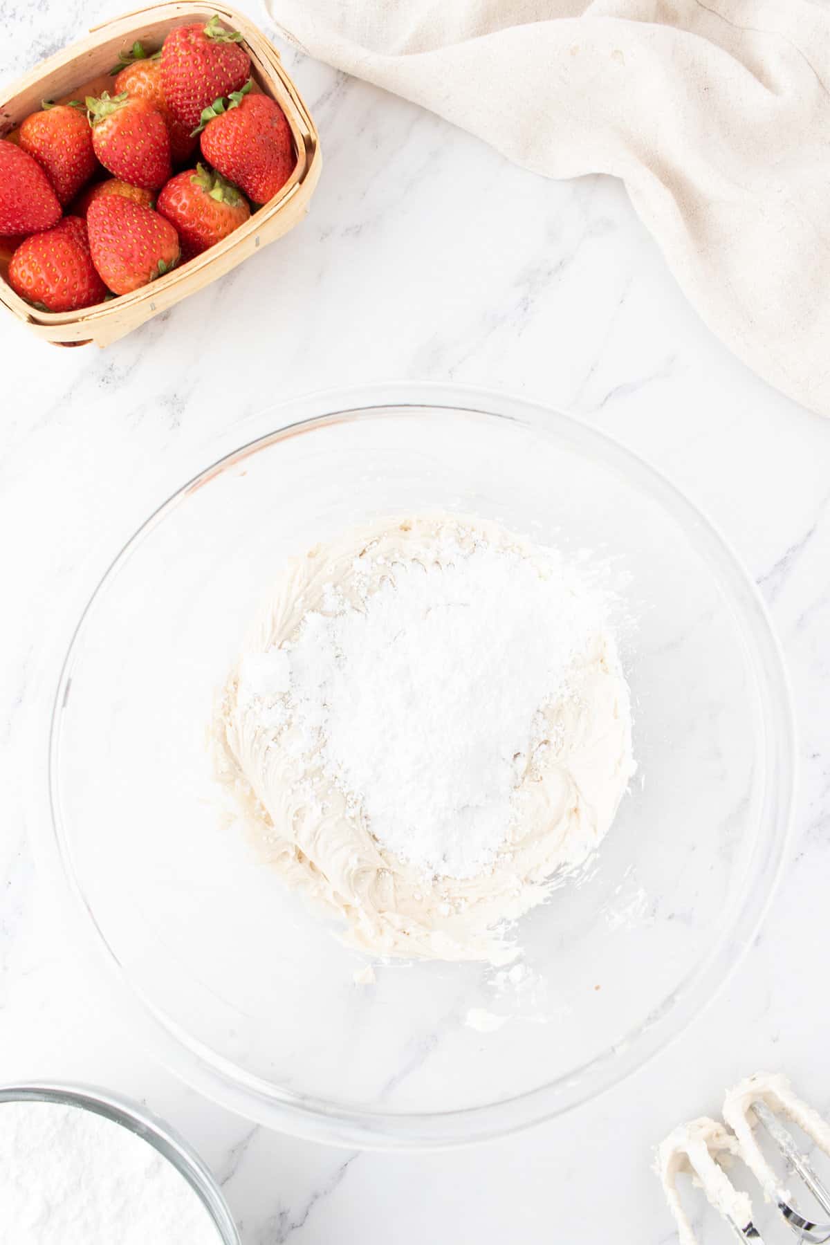 powdered sugar on top of cream cheese and butter mixture in a mixing bowl