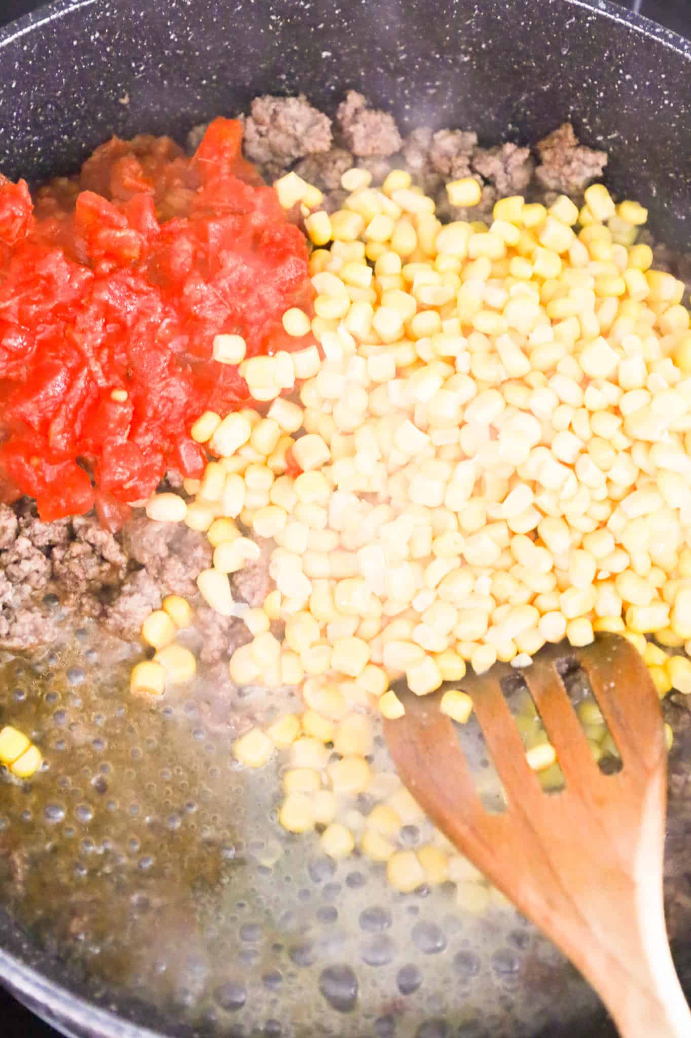Rotel and canned corn kernels added to skillet with cooked ground beef