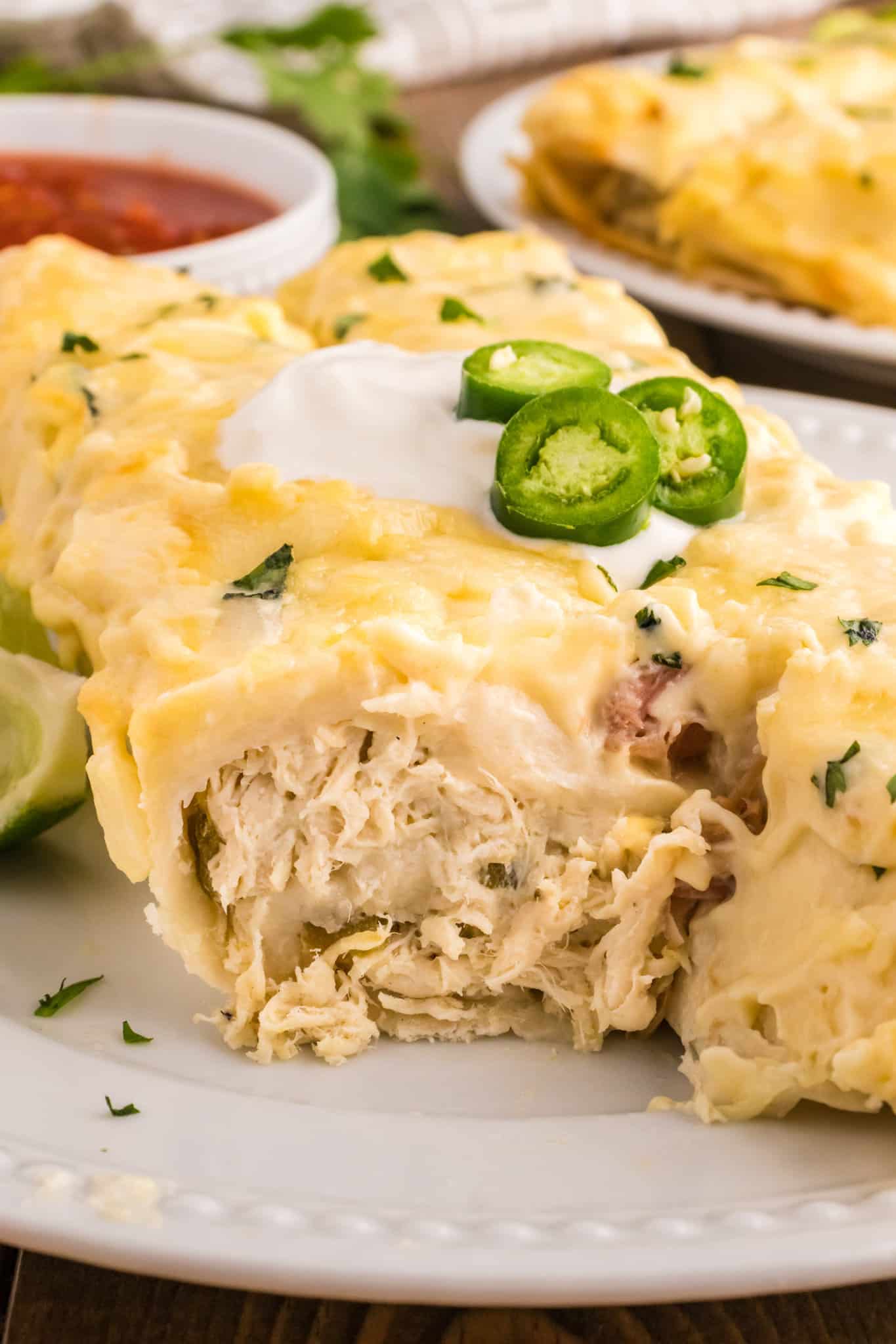 White Chicken Enchiladas are delicious baked tortillas filled with shredded chicken, cream cheese and green chilis baked in a creamy sauce and topped with cheese.