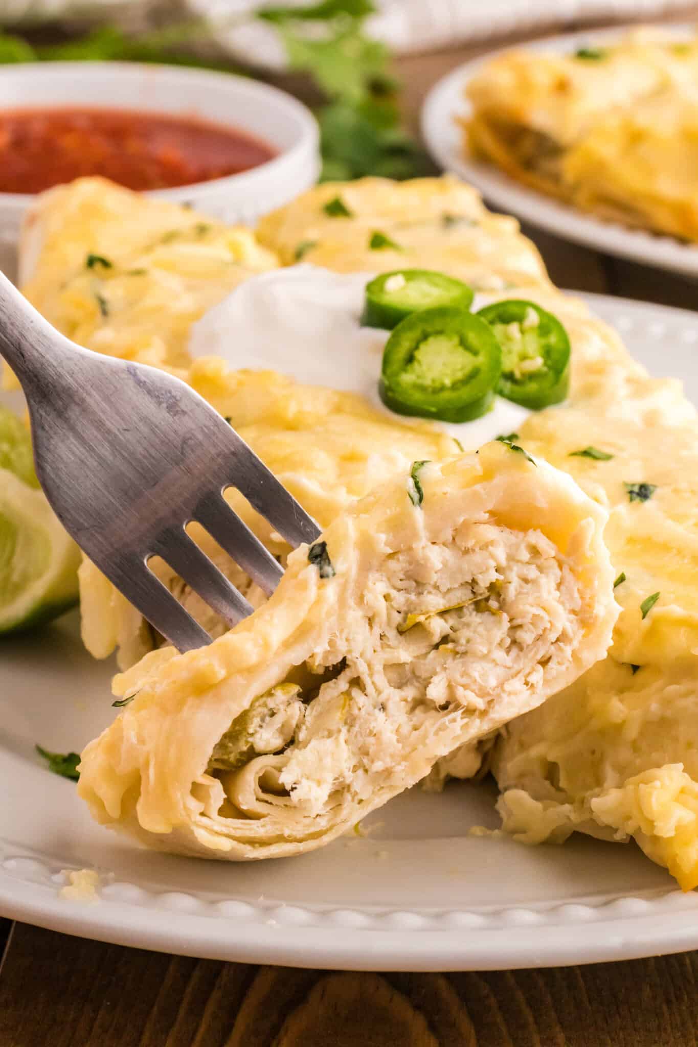 White Chicken Enchiladas are delicious baked tortillas filled with shredded chicken, cream cheese and green chilis baked in a creamy sauce and topped with cheese.