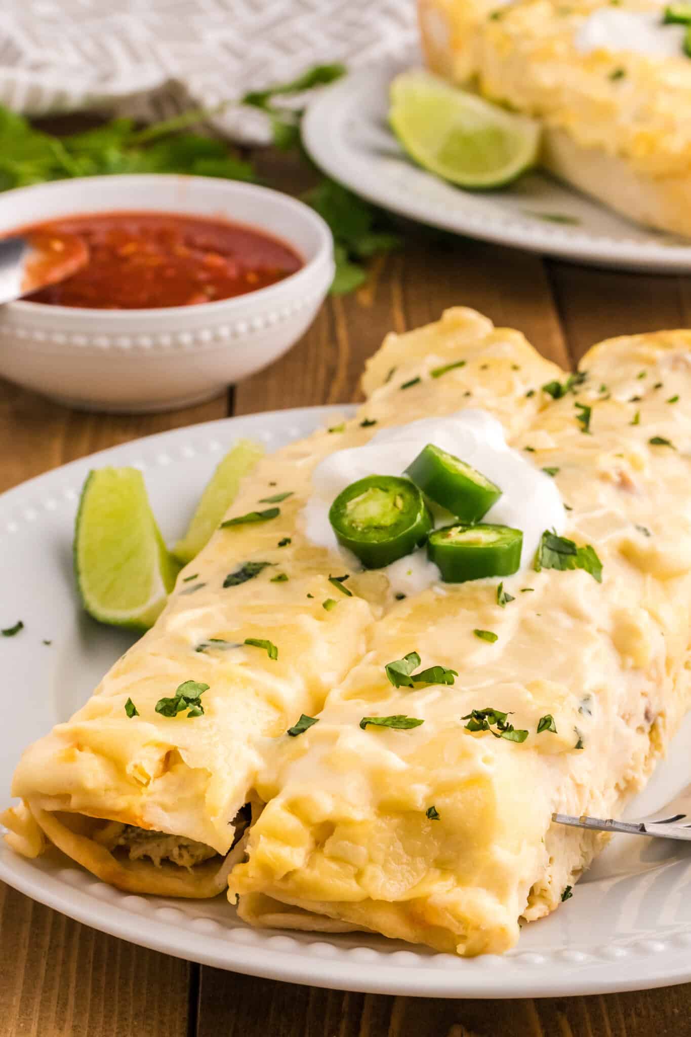 White Chicken Enchiladas are delicious baked tortillas filled with shredded chicken, cream cheese and green chilis baked in a creamy sauce and topped with cheese.