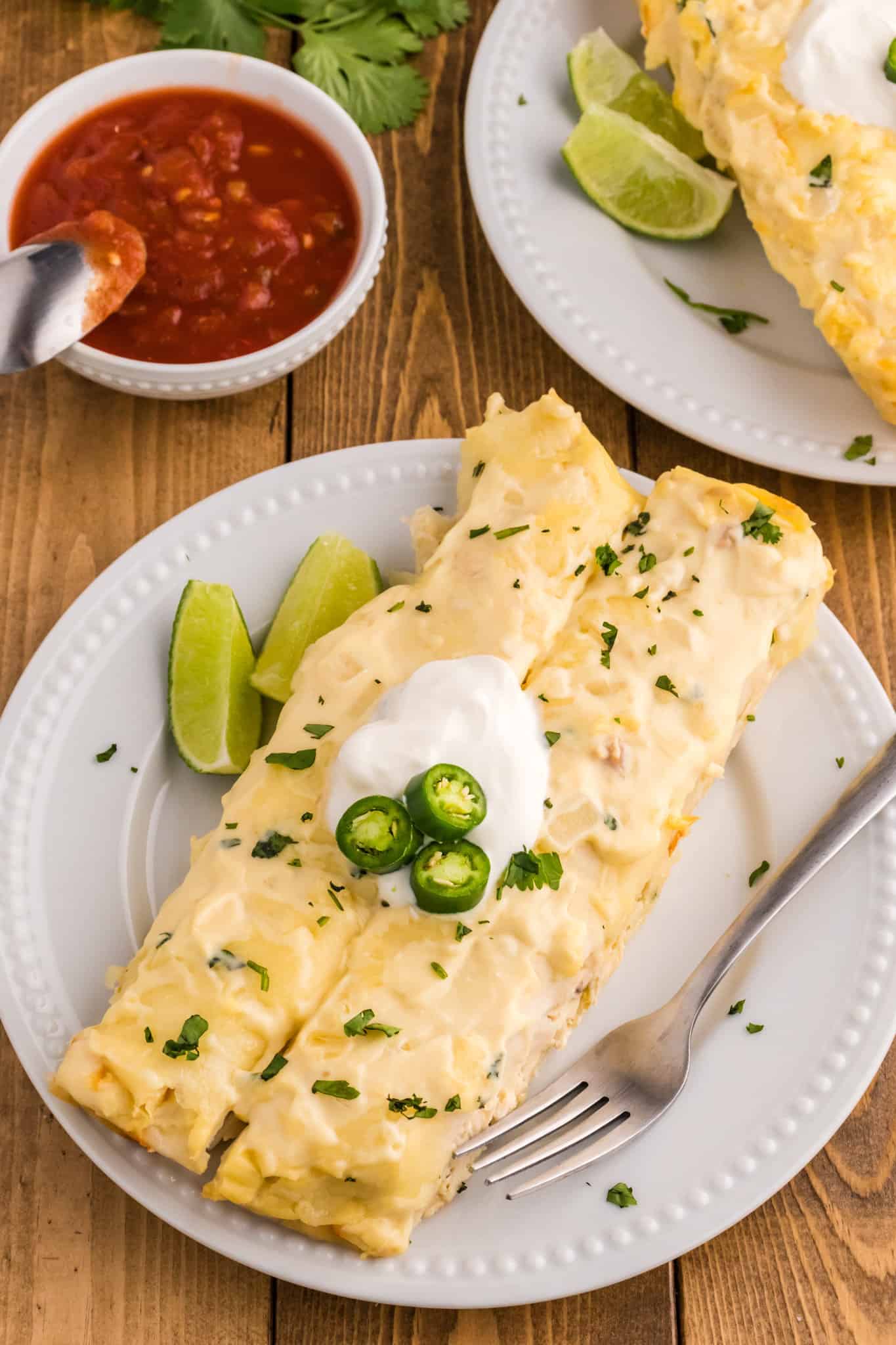 White Chicken Enchiladas are delicious baked tortillas filled with shredded chicken, cream cheese and green chilis baked in a creamy sauce and topped with cheese.