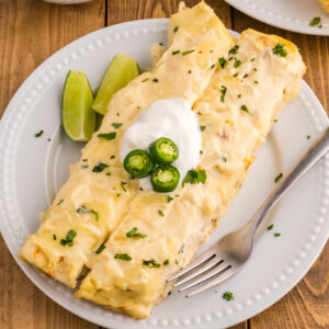 White Chicken Enchiladas are delicious baked tortillas filled with shredded chicken, cream cheese and green chilis baked in a creamy sauce and topped with cheese.