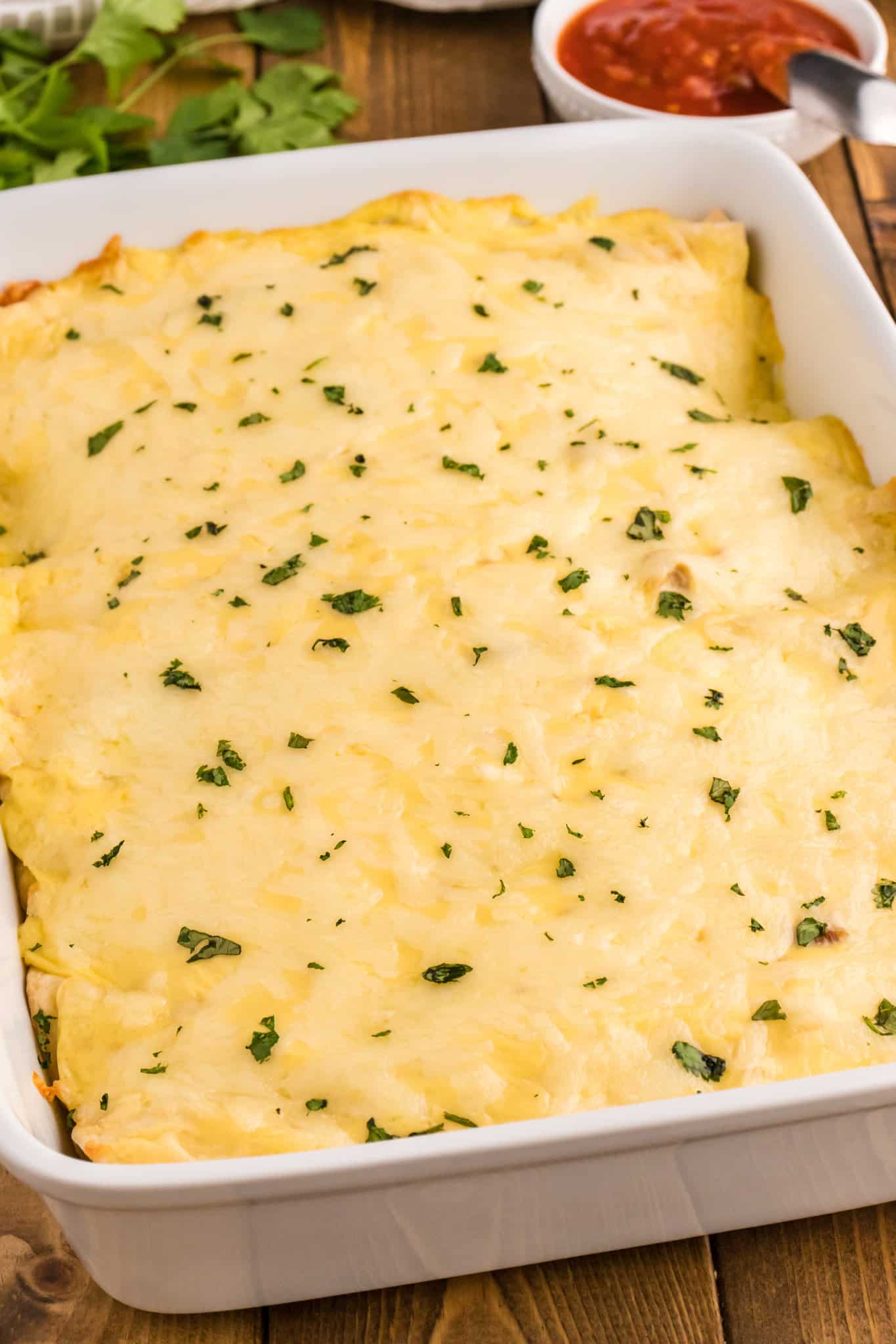 White Chicken Enchiladas are delicious baked tortillas filled with shredded chicken, cream cheese and green chilis baked in a creamy sauce and topped with cheese.