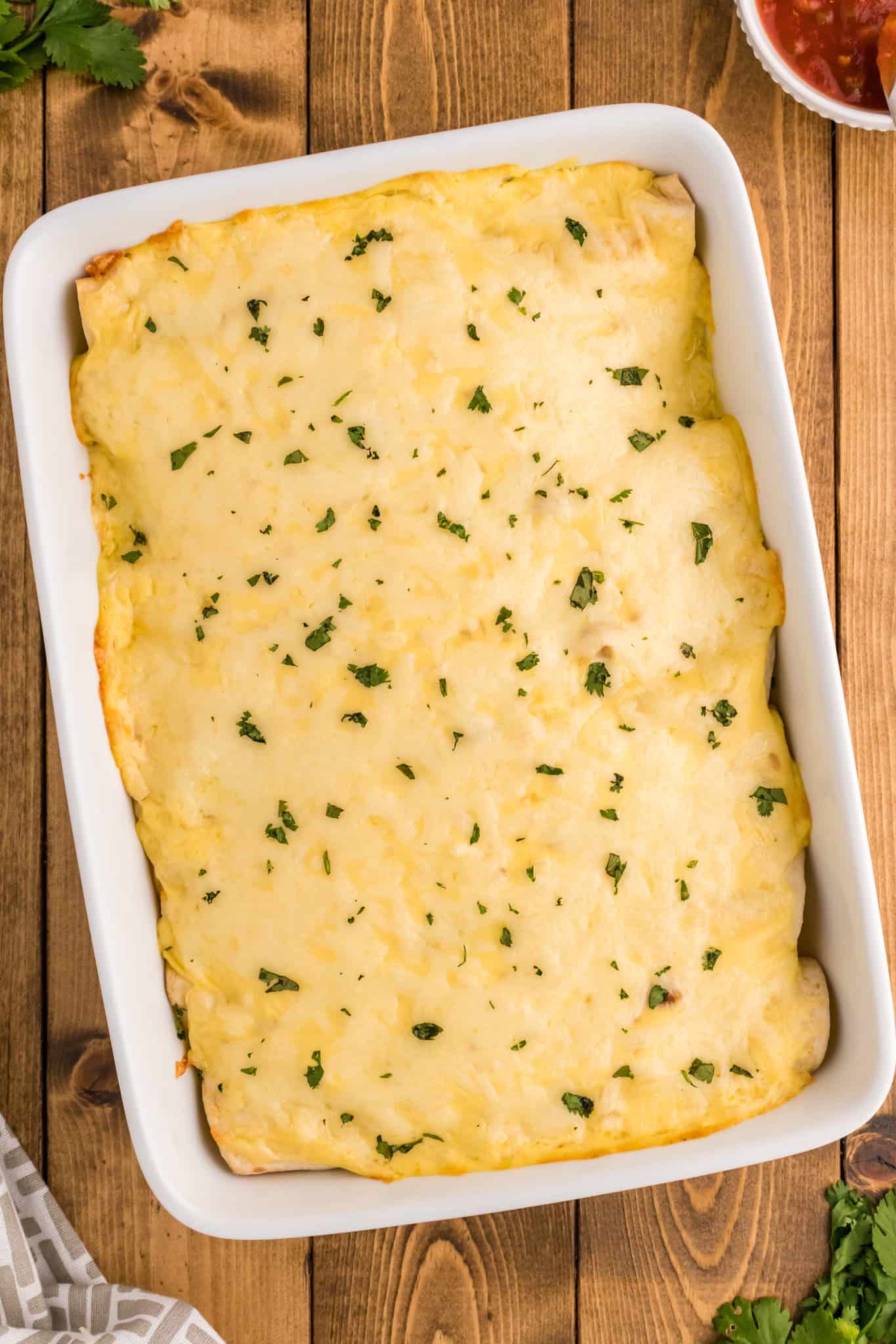 White Chicken Enchiladas are delicious baked tortillas filled with shredded chicken, cream cheese and green chilis baked in a creamy sauce and topped with cheese.