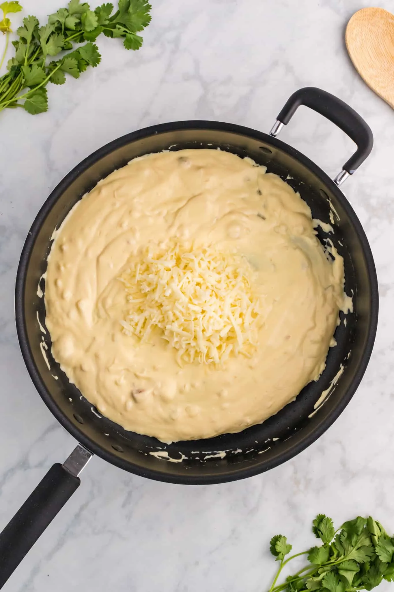 shredded Monterey jack cheese on top of cream of chicken soup and sour cream mixture in a pan