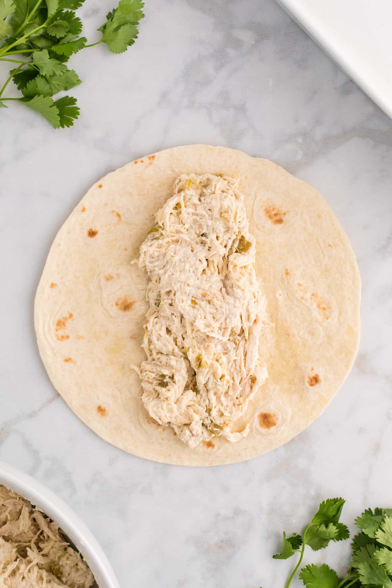 creamy shredded chicken mixture in the center of a tortilla