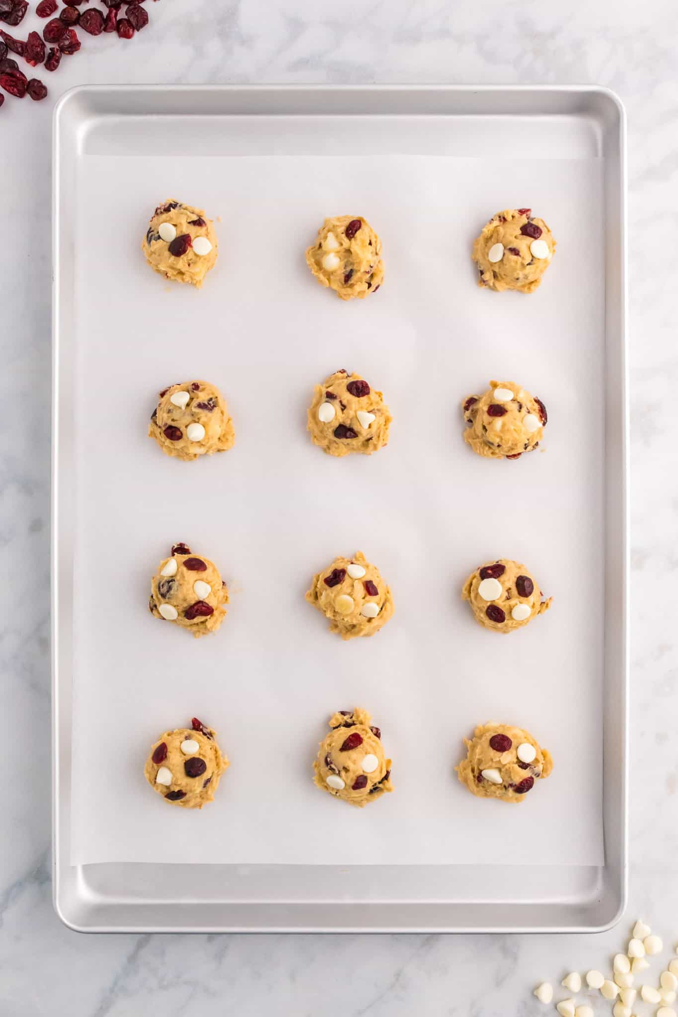 white chocolate cranberry oatmeal cookie dough balls on a parchment lined baking sheet
