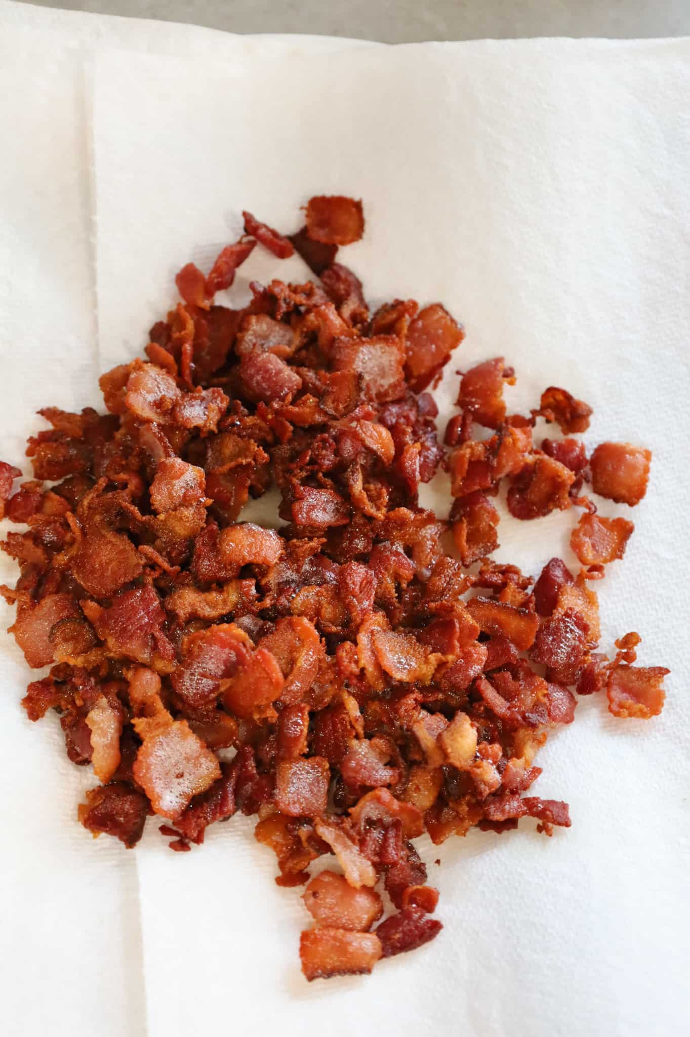 cooked bacon pieces on top of paper towel on a plate