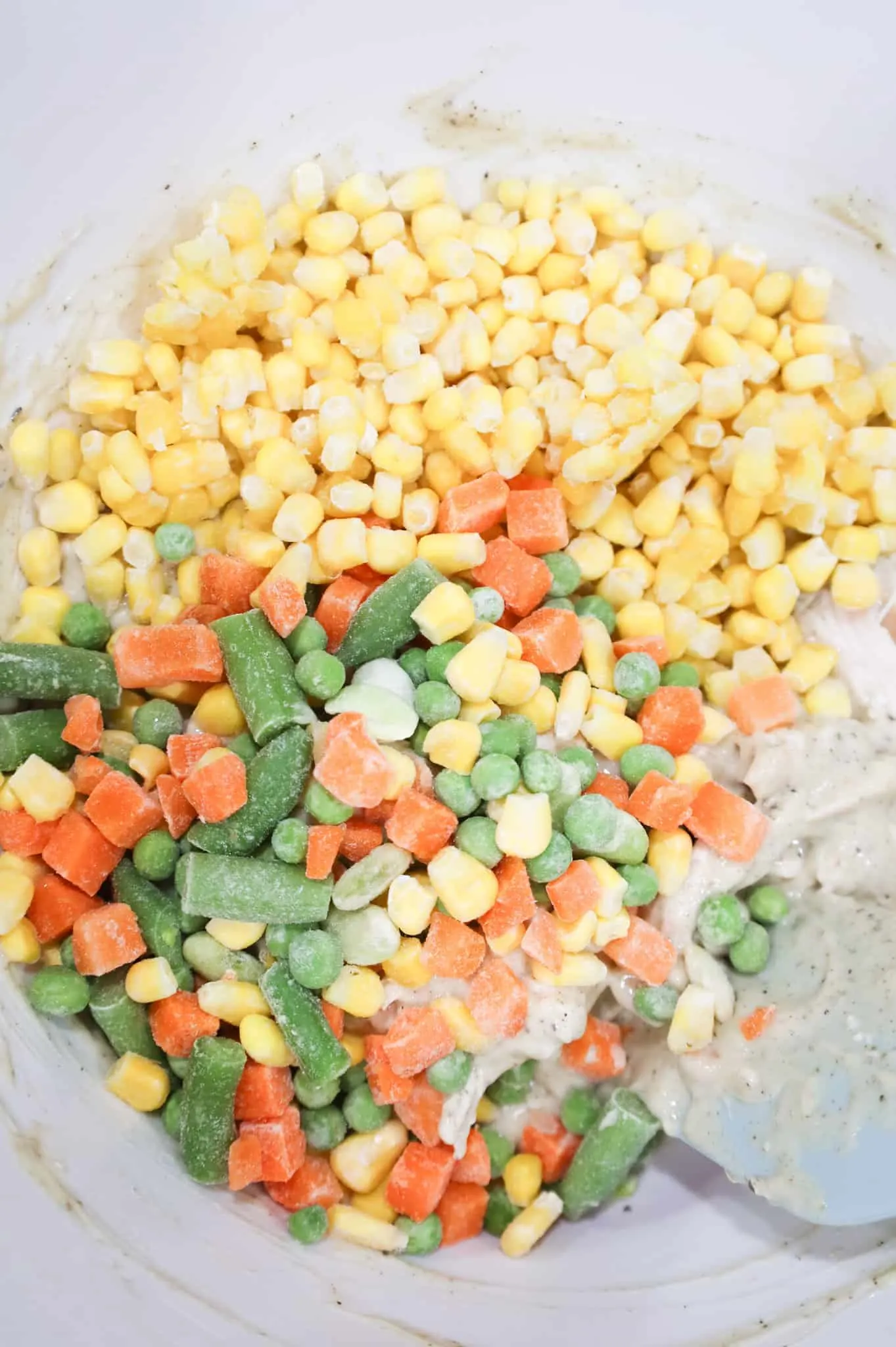 frozen mixed veggies and frozen corn added to bowl with cream soup and chicken mixture