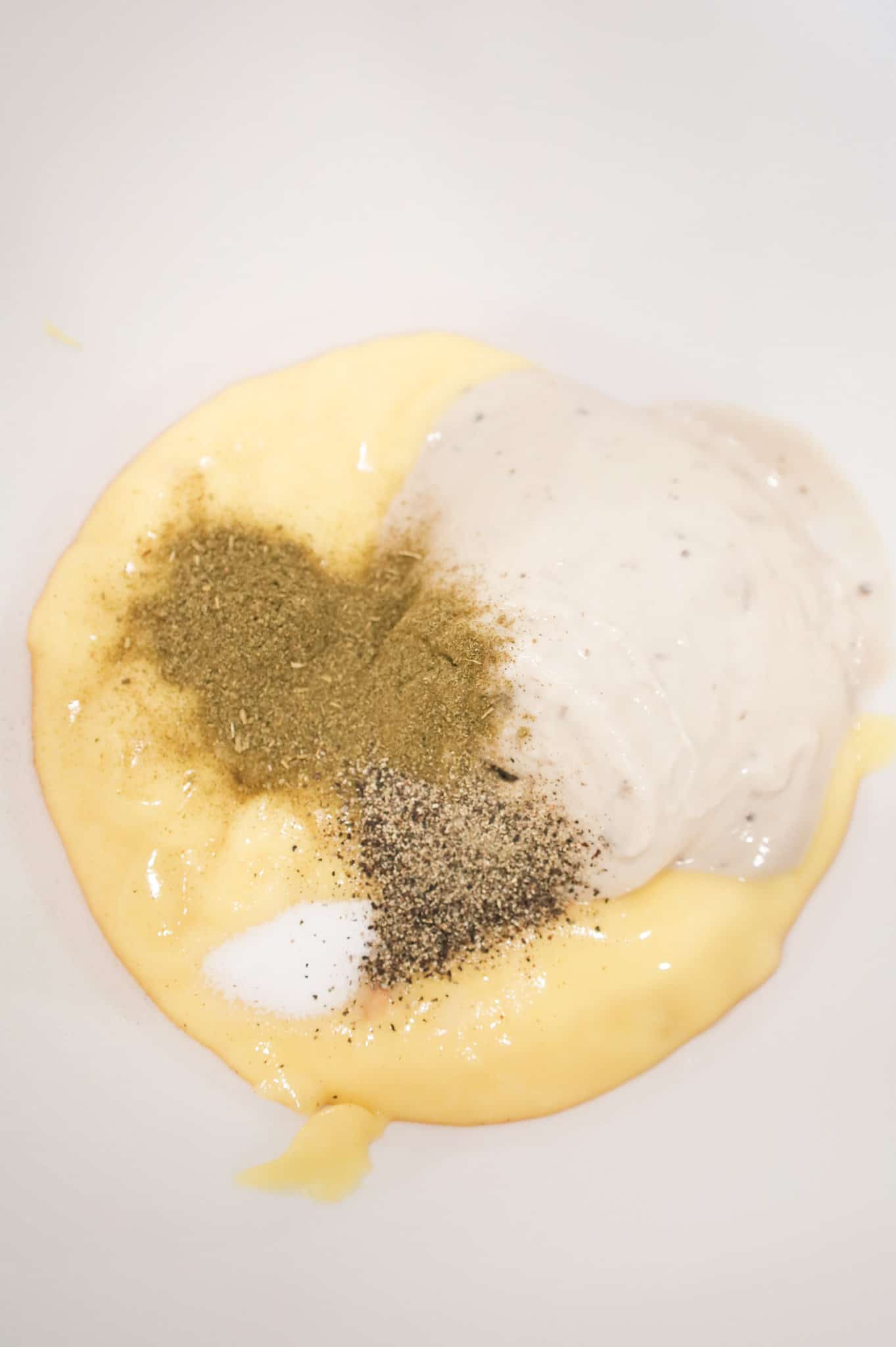 poultry seasoning, salt and pepper on top of cream of mushroom and cream of chicken soup in a mixing bowl