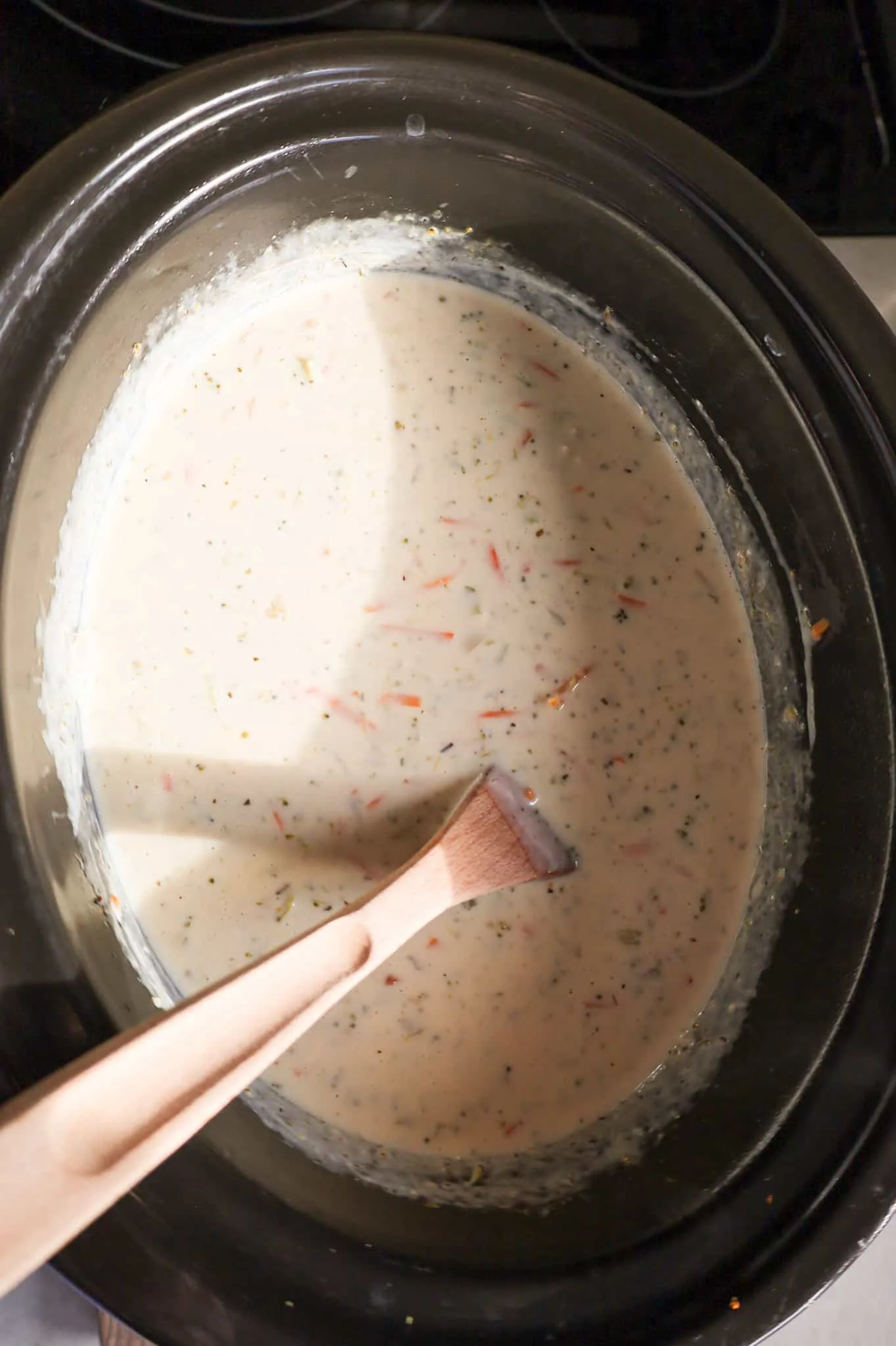 stirring heavy cream into broccoli soup mixture in a crock pot