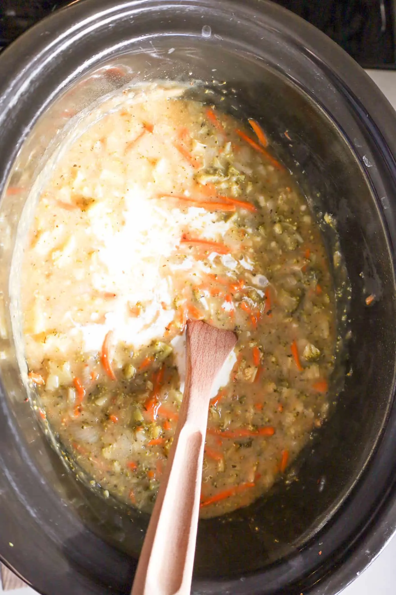 heaving cream added to crock pot with cooked broccoli soup ingredients