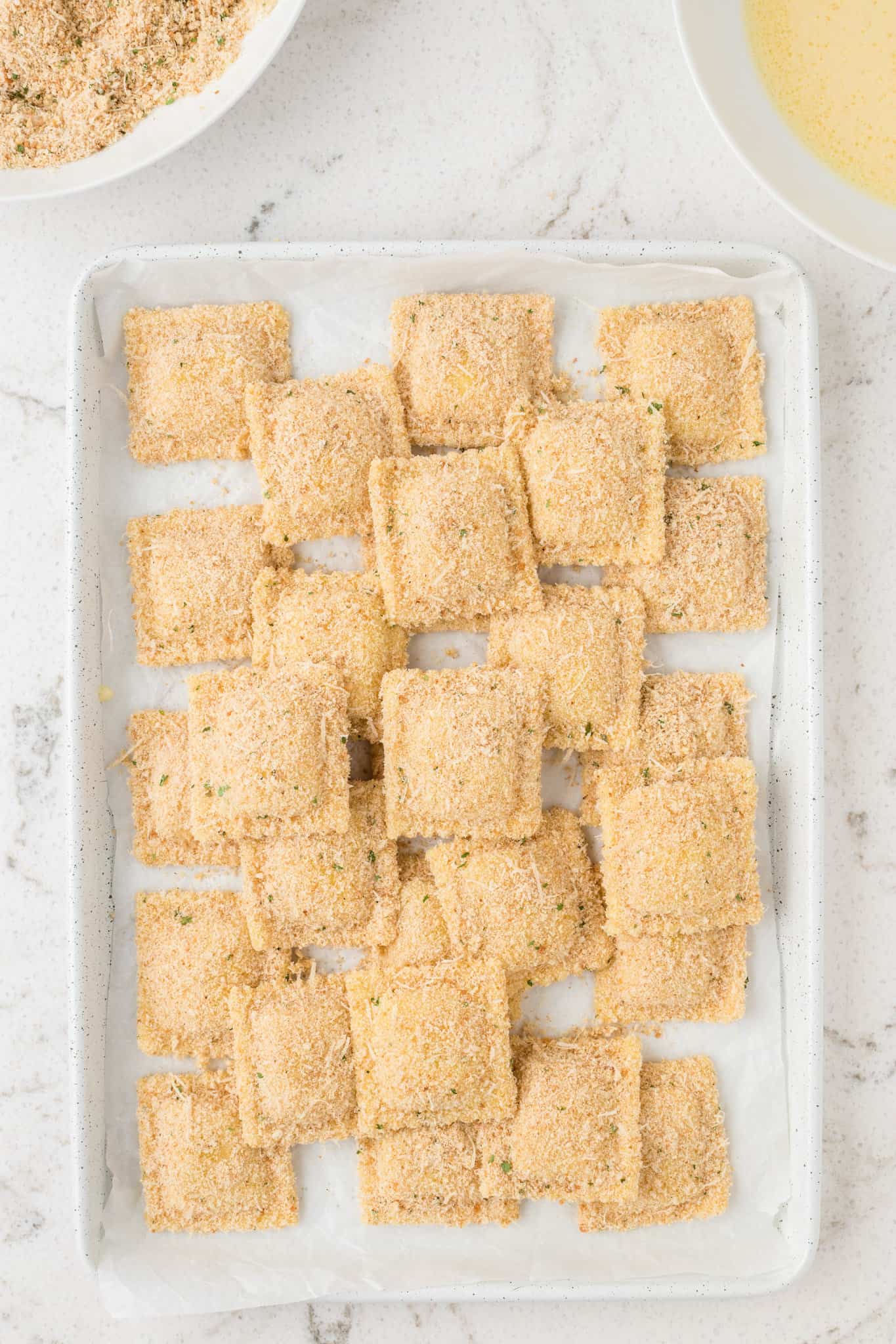 breaded ravioli on a parchment lined pan