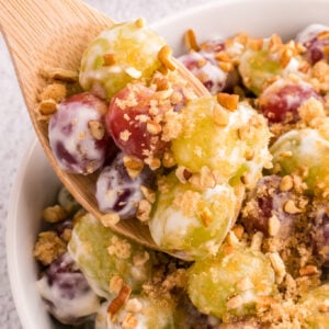 Grape Salad is a tasty side dish loaded with red and green grapes all tossed in a cream cheese and yogurt mixture and topped with brown sugar and chopped pecans.