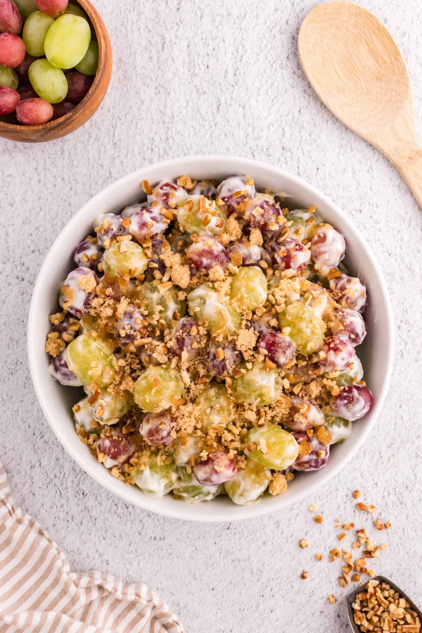 Grape Salad is a tasty side dish loaded with red and green grapes all tossed in a cream cheese and yogurt mixture and topped with brown sugar and chopped pecans.