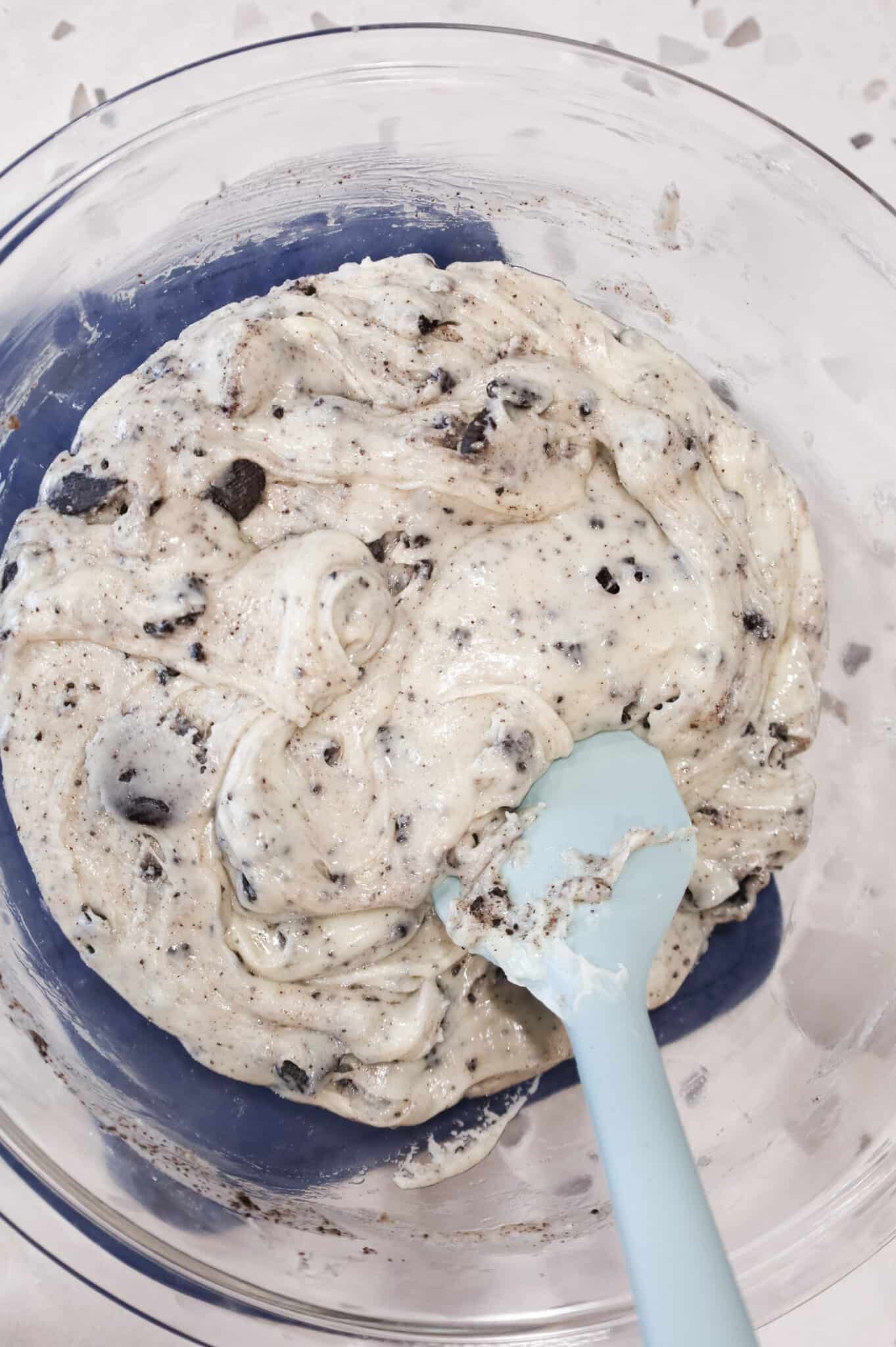 stirring crumbled Oreos into white chocolate mixture in a mixing bowl