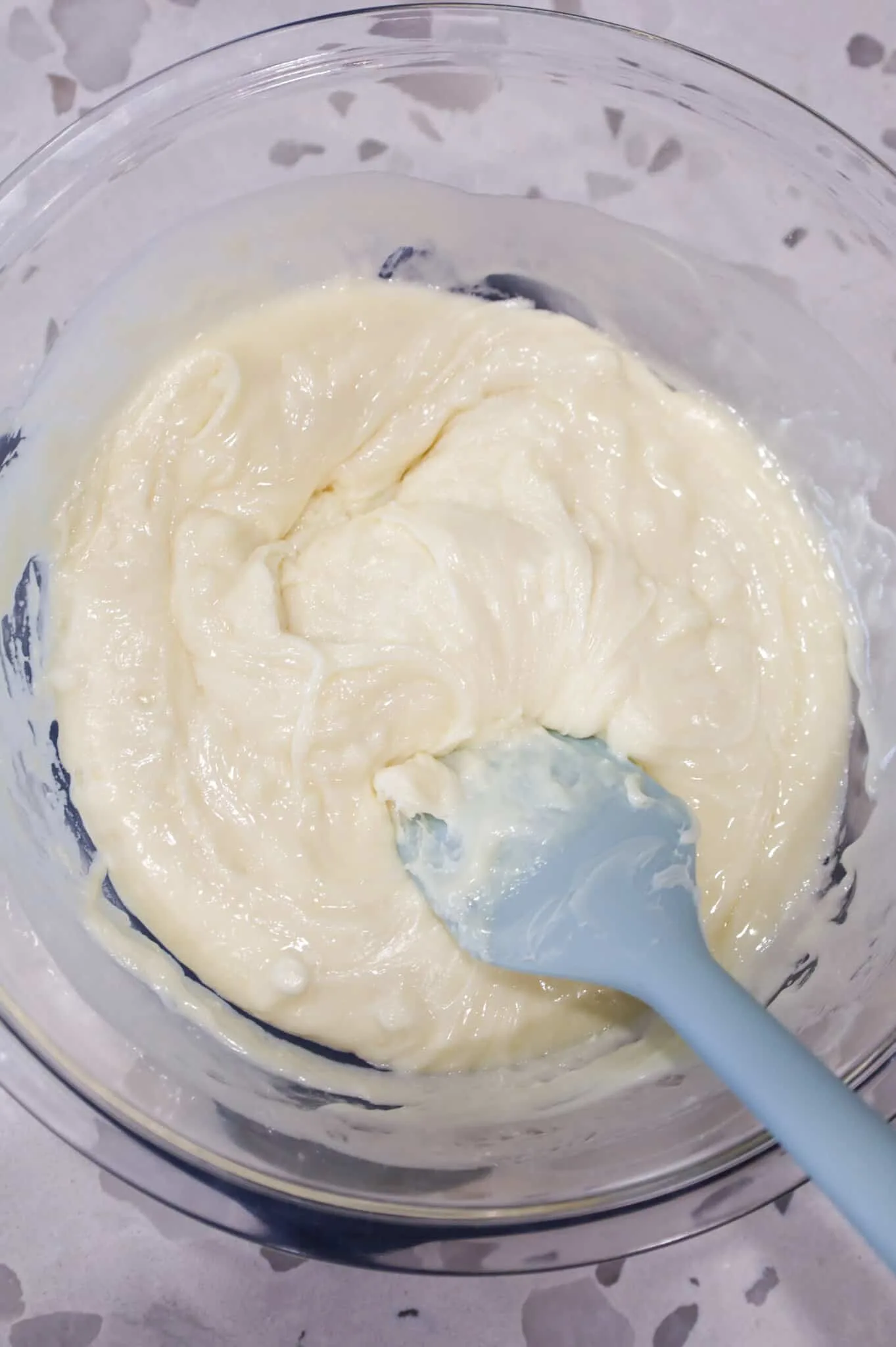 stirring white chocolate chips and vanilla frosting in a bowl