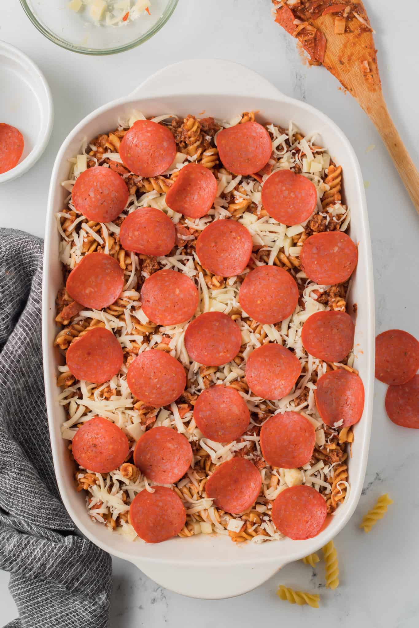 pepperoni slices on top of pizza pasta in a baking dish