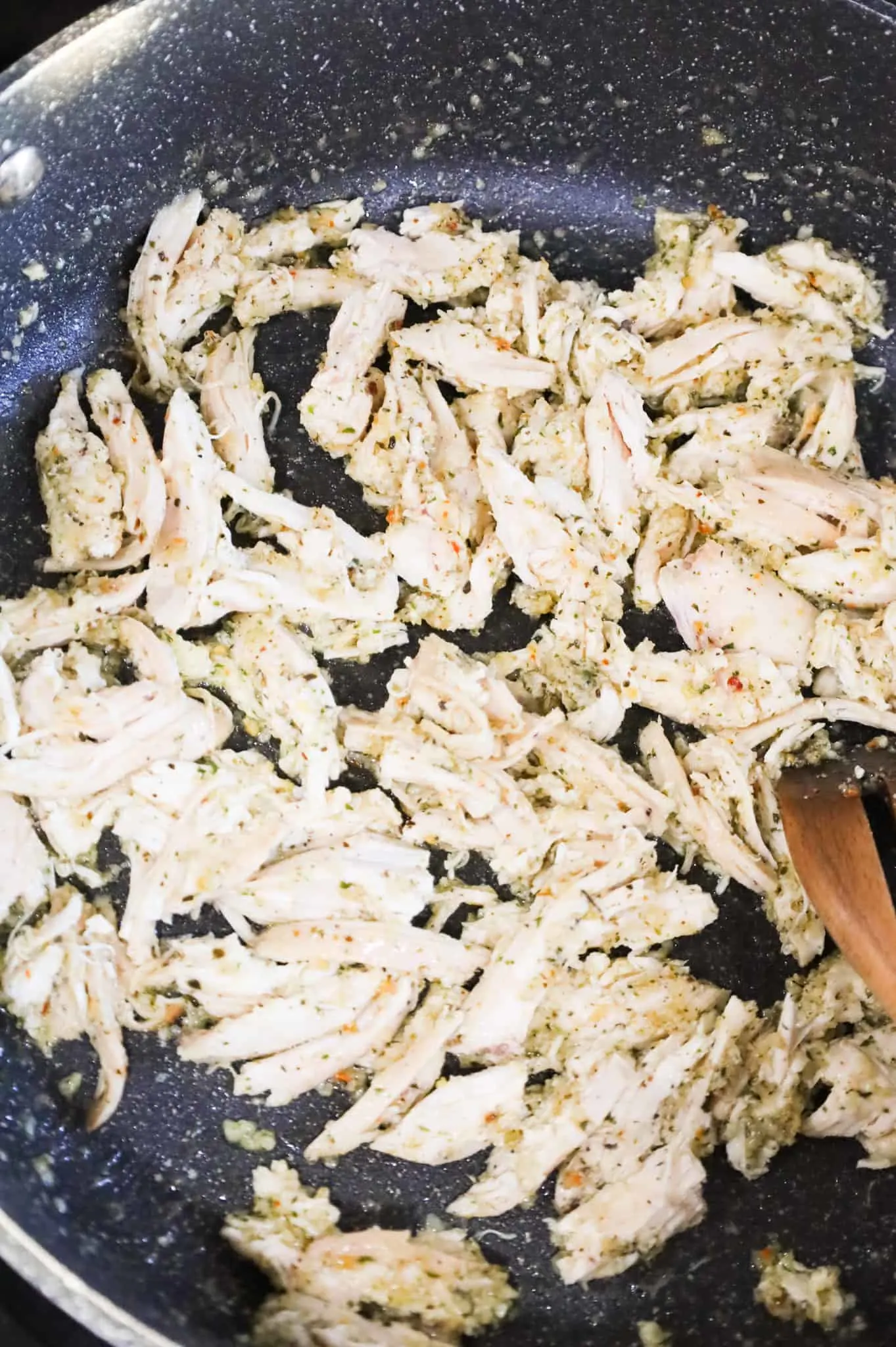 shredded chicken coated in Italian seasoning in a skillet