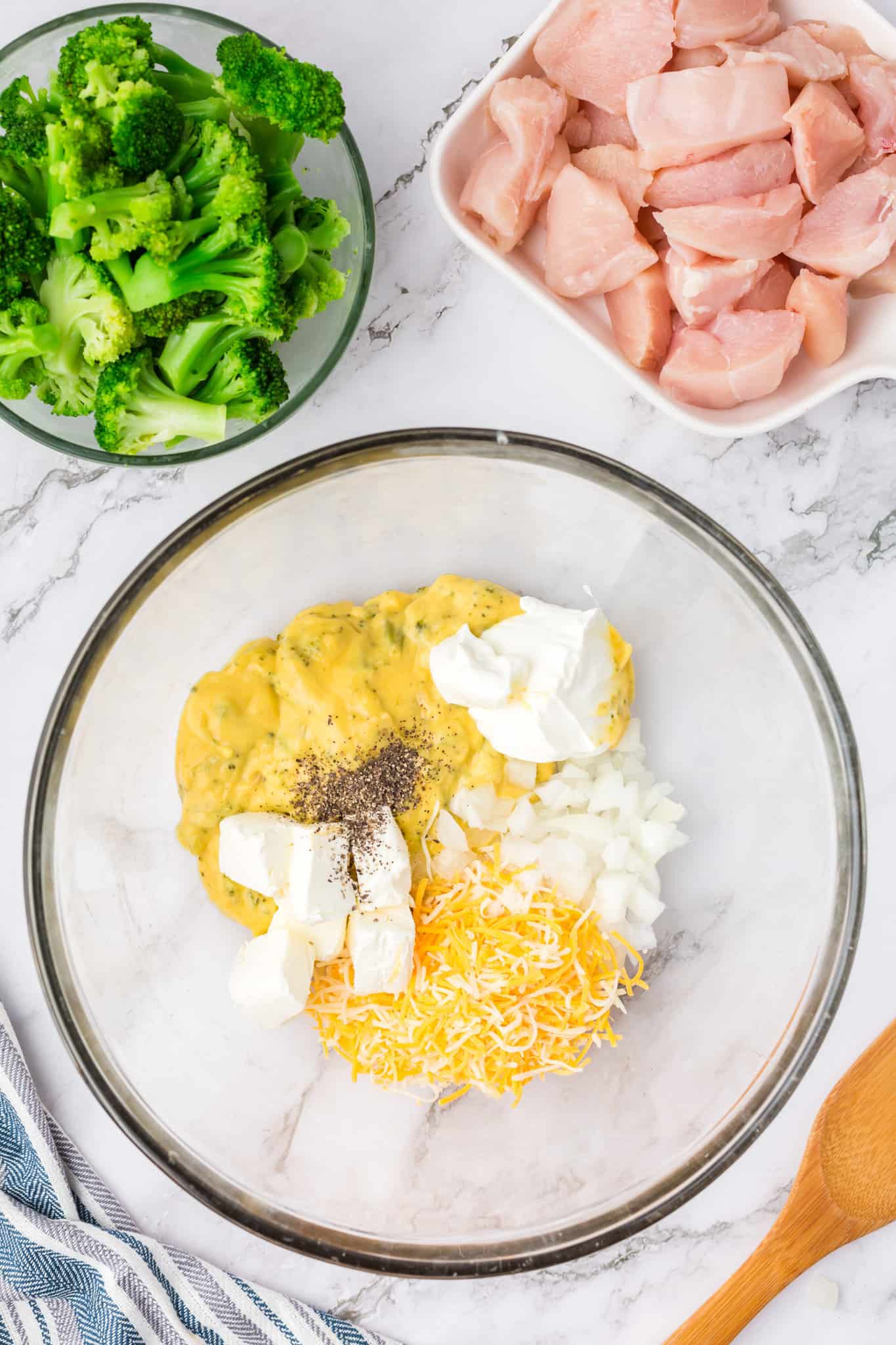 cream cheese, sour cream, Velveeta, cream of broccoli soup, shredded cheese and spices in a mixing bowl