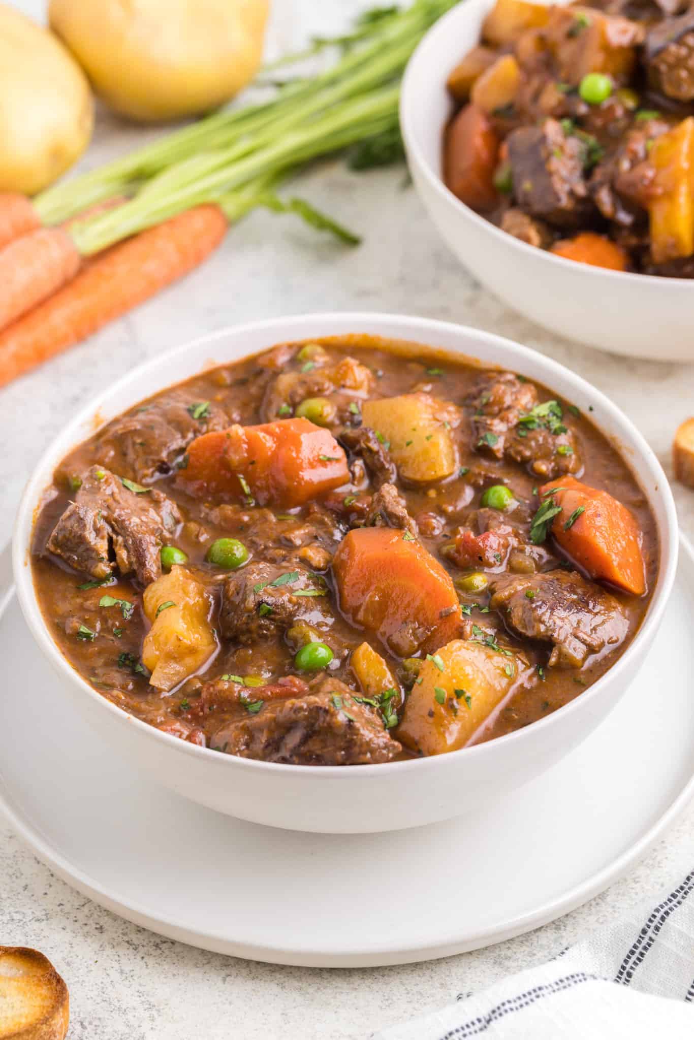 Dutch Oven Beef Stew is a hearty dish loaded with chunks of beef, carrots, onions, potatoes, tomatoes and peas.