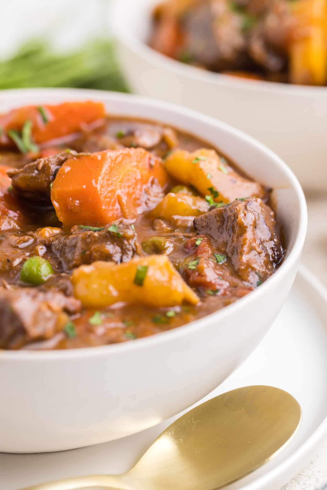 Dutch Oven Beef Stew is a hearty dish loaded with chunks of beef, carrots, onions, potatoes, tomatoes and peas.