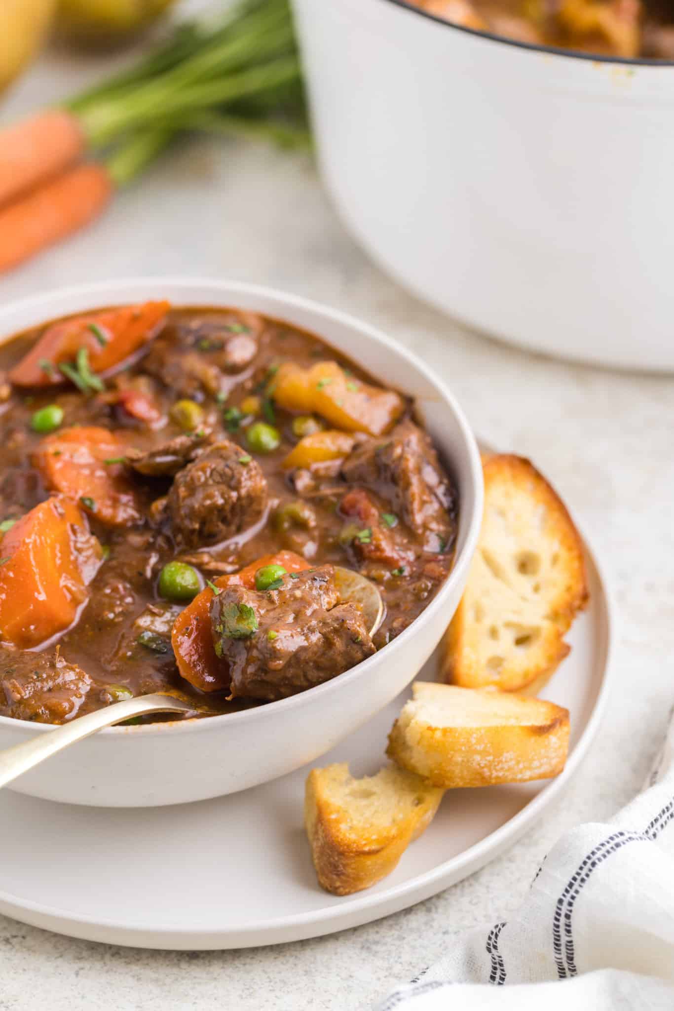 Dutch Oven Beef Stew is a hearty dish loaded with chunks of beef, carrots, onions, potatoes, tomatoes and peas.