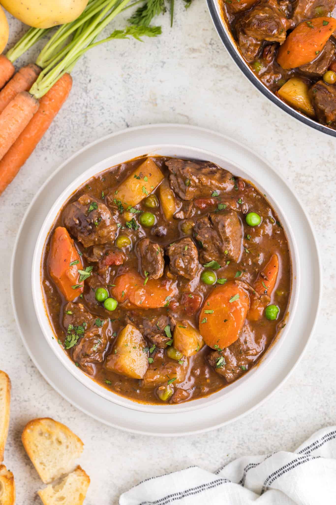 Dutch Oven Beef Stew is a hearty dish loaded with chunks of beef, carrots, onions, potatoes, tomatoes and peas.