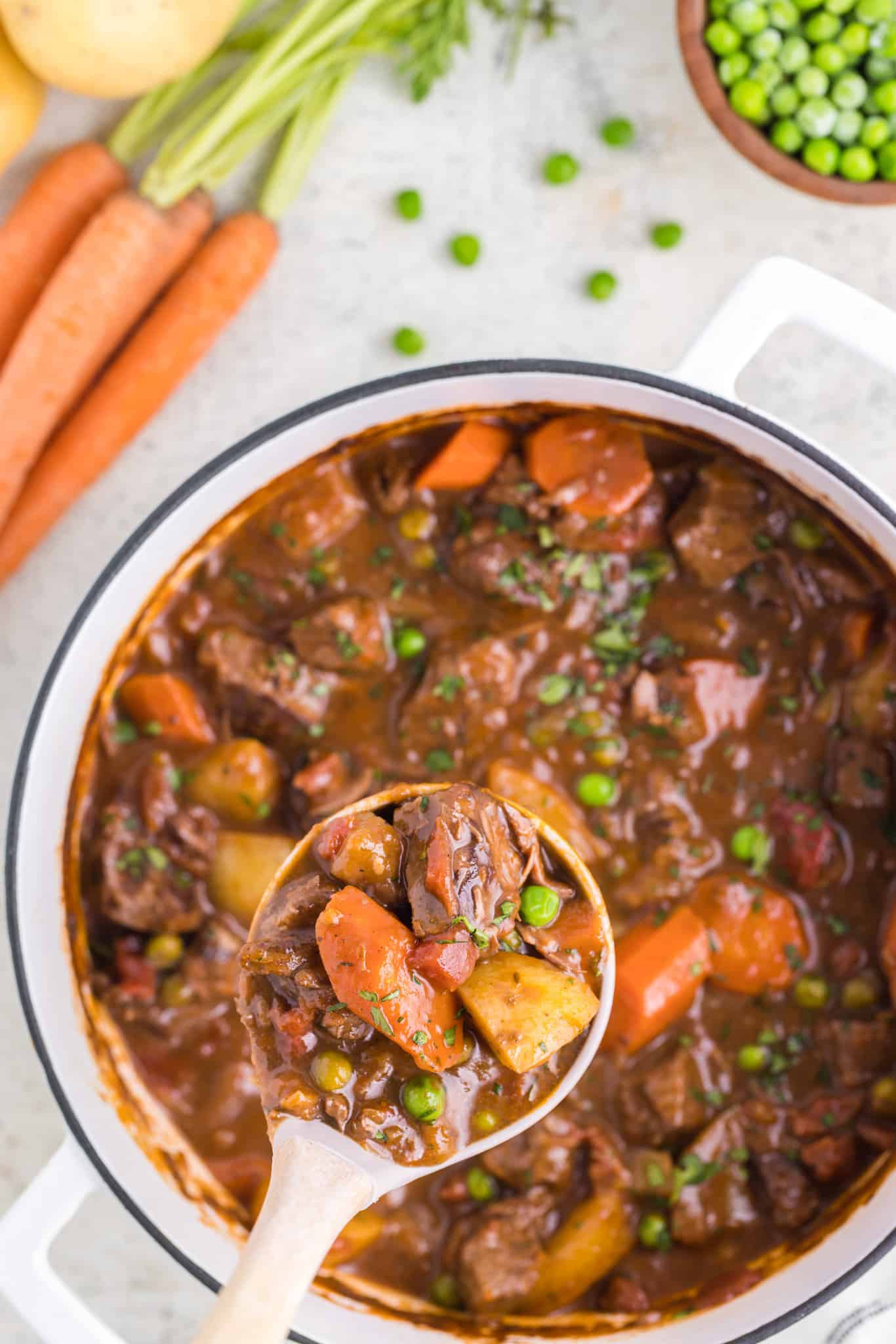 Dutch Oven Beef Stew is a hearty dish loaded with chunks of beef, carrots, onions, potatoes, tomatoes and peas.