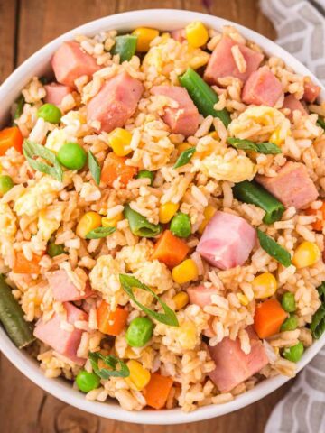 Ham Fried Rice is a delicious dinner or side dish recipe using diced ham, scrambled eggs and frozen mixed veggies all tossed with rice, soy sauce and fried rice seasoning mix.