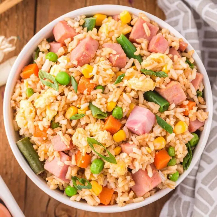 Ham Fried Rice is a delicious dinner or side dish recipe using diced ham, scrambled eggs and frozen mixed veggies all tossed with rice, soy sauce and fried rice seasoning mix.